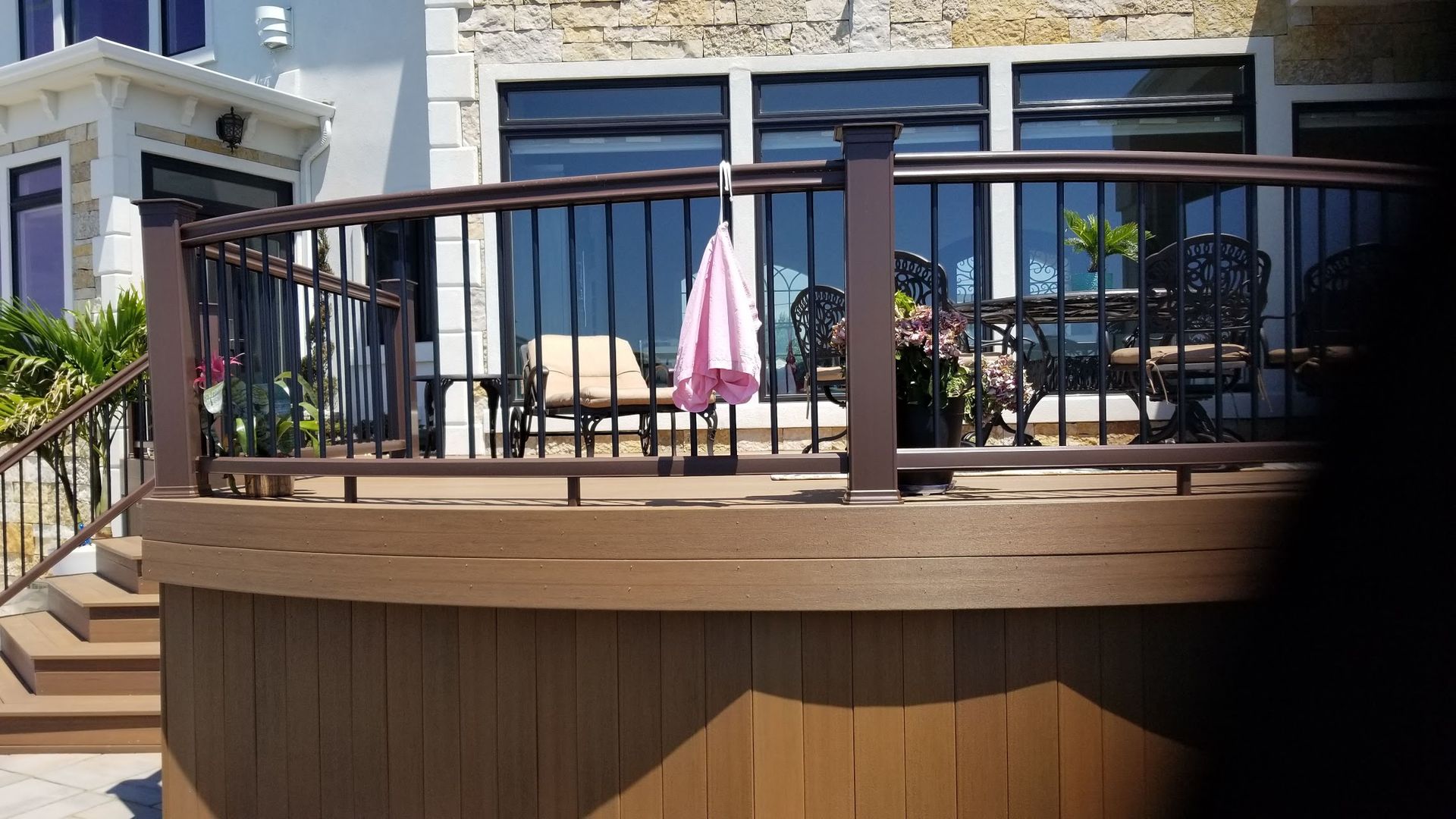 A wooden deck with a metal railing and a pink umbrella hanging from it