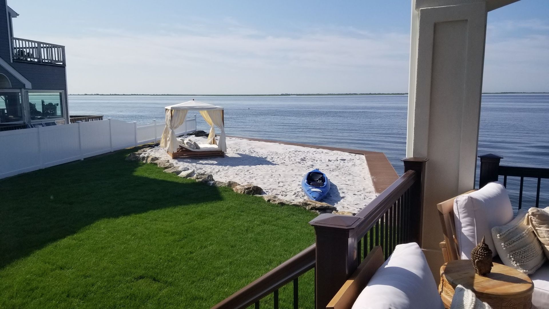 A view of the ocean from a balcony with a canopy bed in the background.