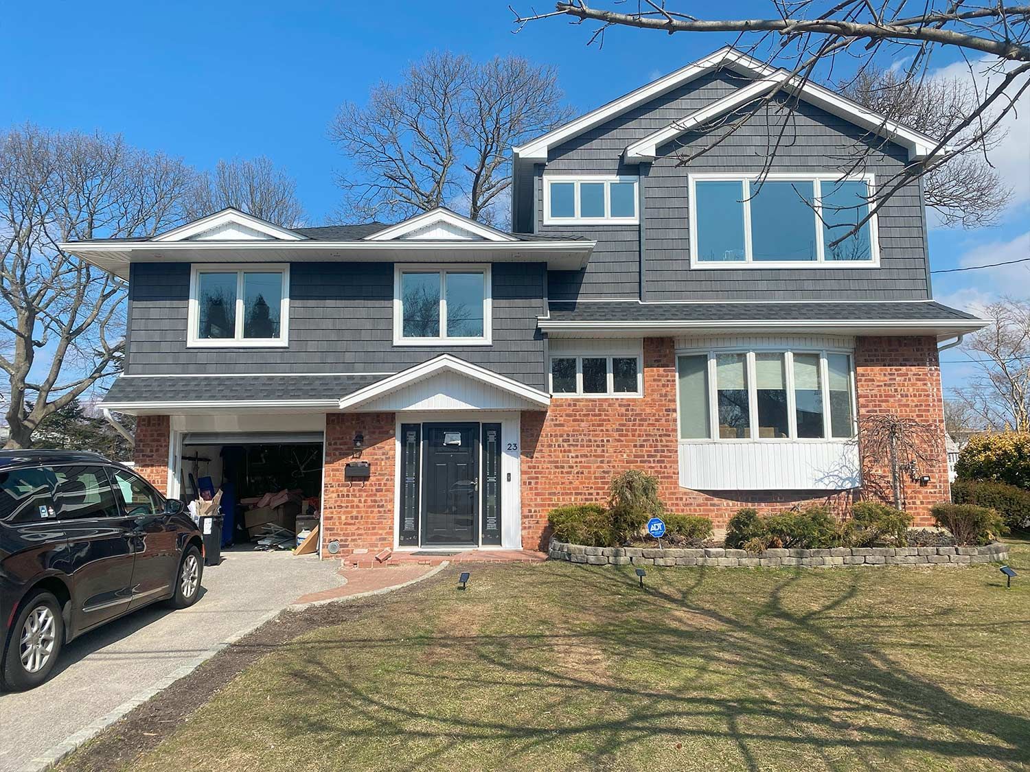 A large brick house with a black car parked in front of it.