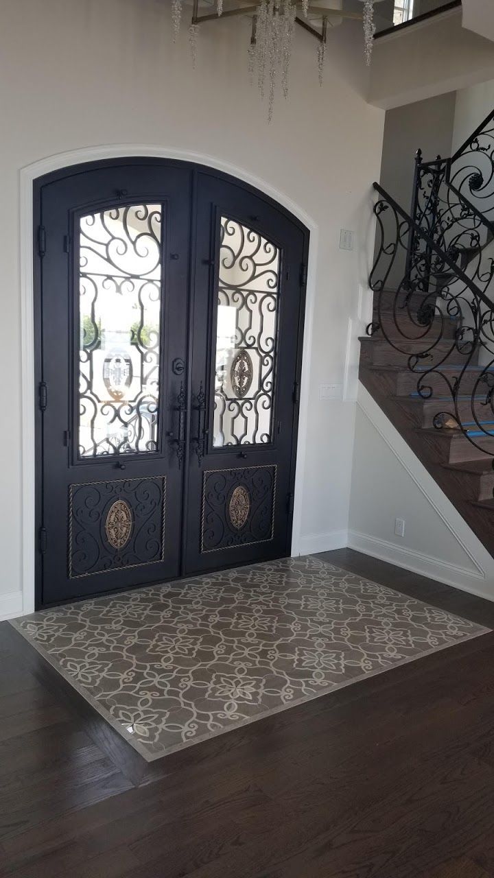A hallway with a wrought iron door and stairs.