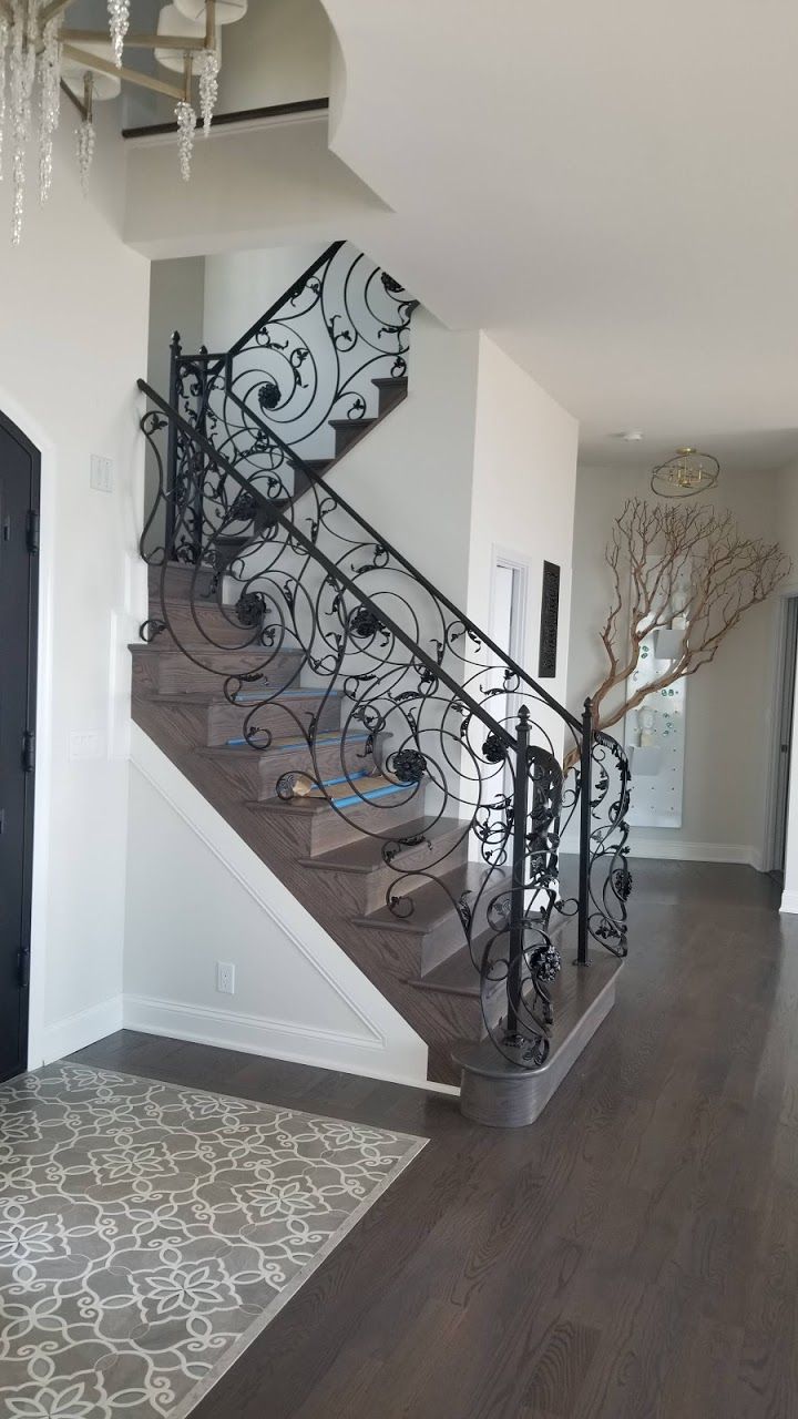 A staircase with a wrought iron railing in a hallway.