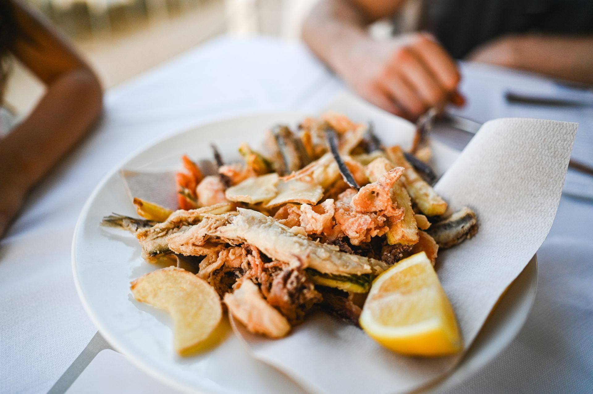 Interno di un ristorante con piante sospese, soffitto curvo e un cuoco che lavora dietro il bancone.