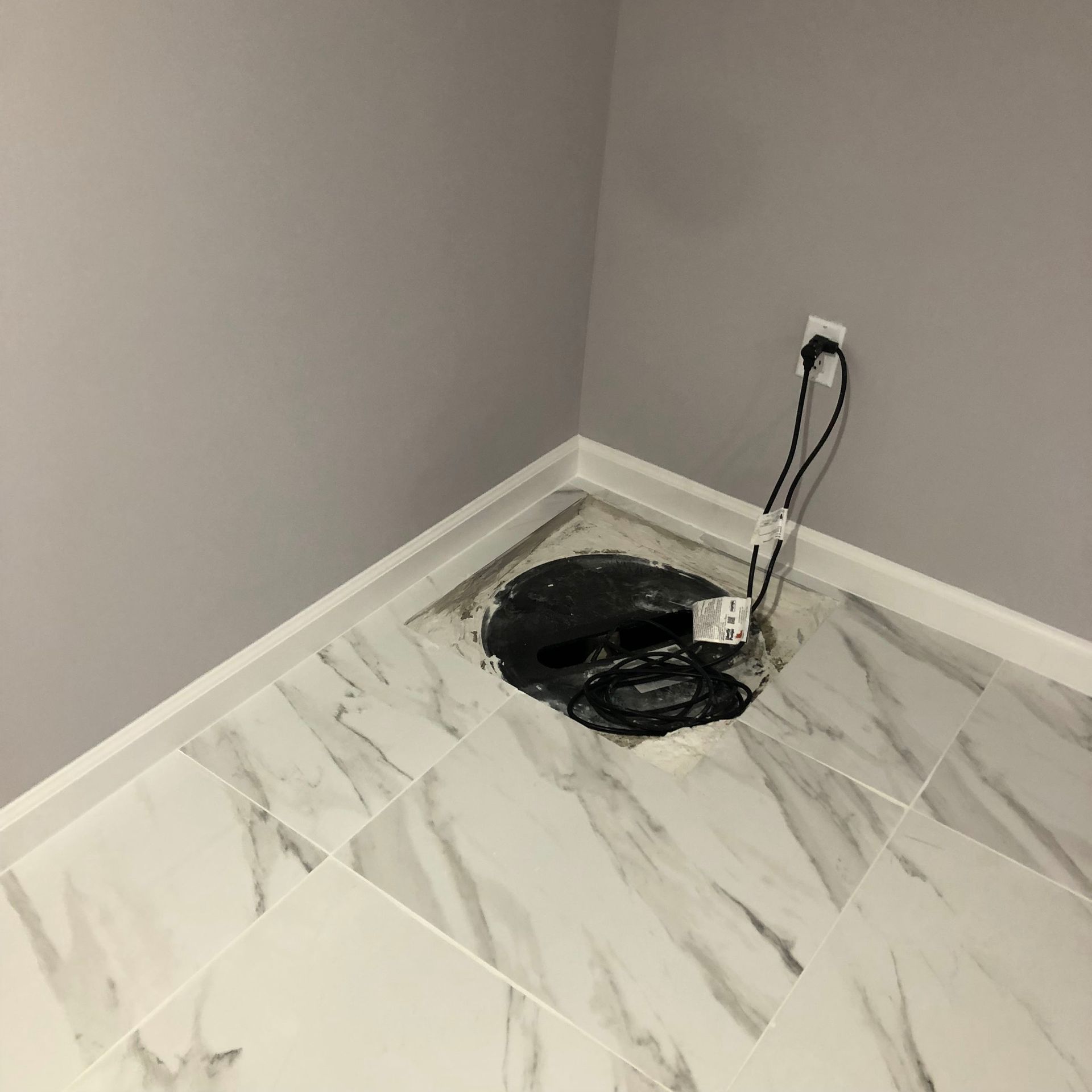 A room with a marble floor and a drain on the floor.