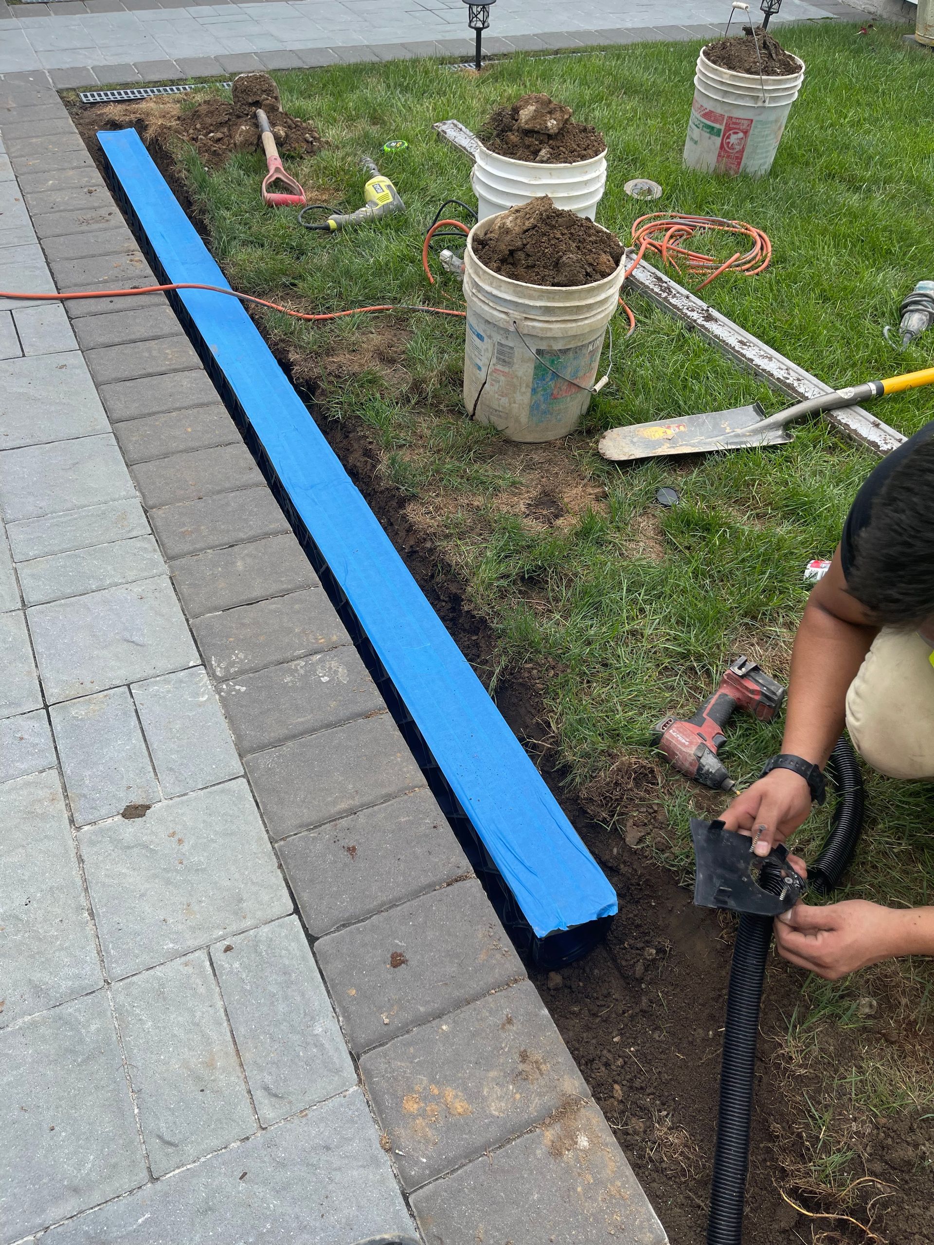 A man is installing a blue fence in a yard.