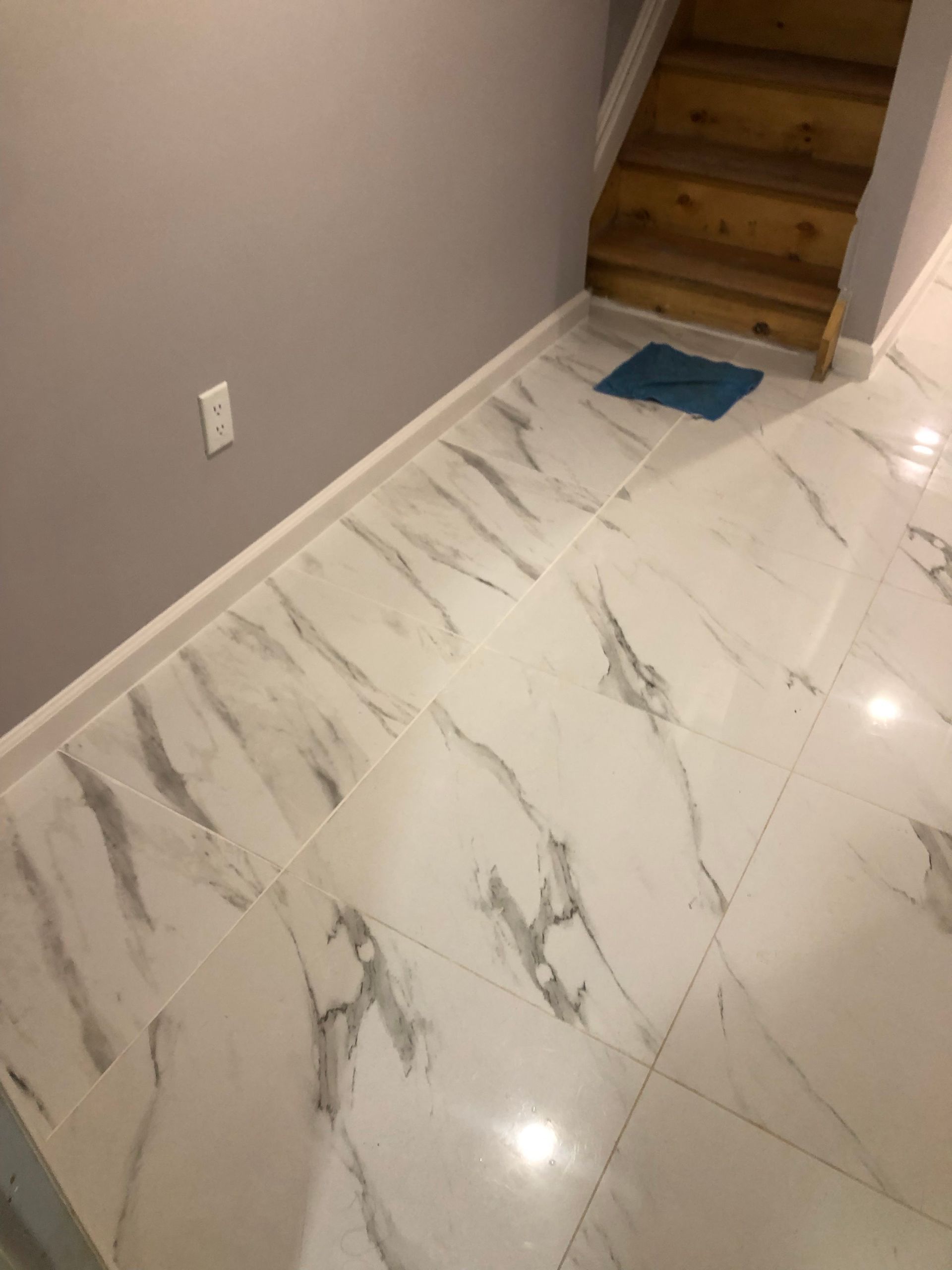 A hallway with white tiles and wooden stairs.