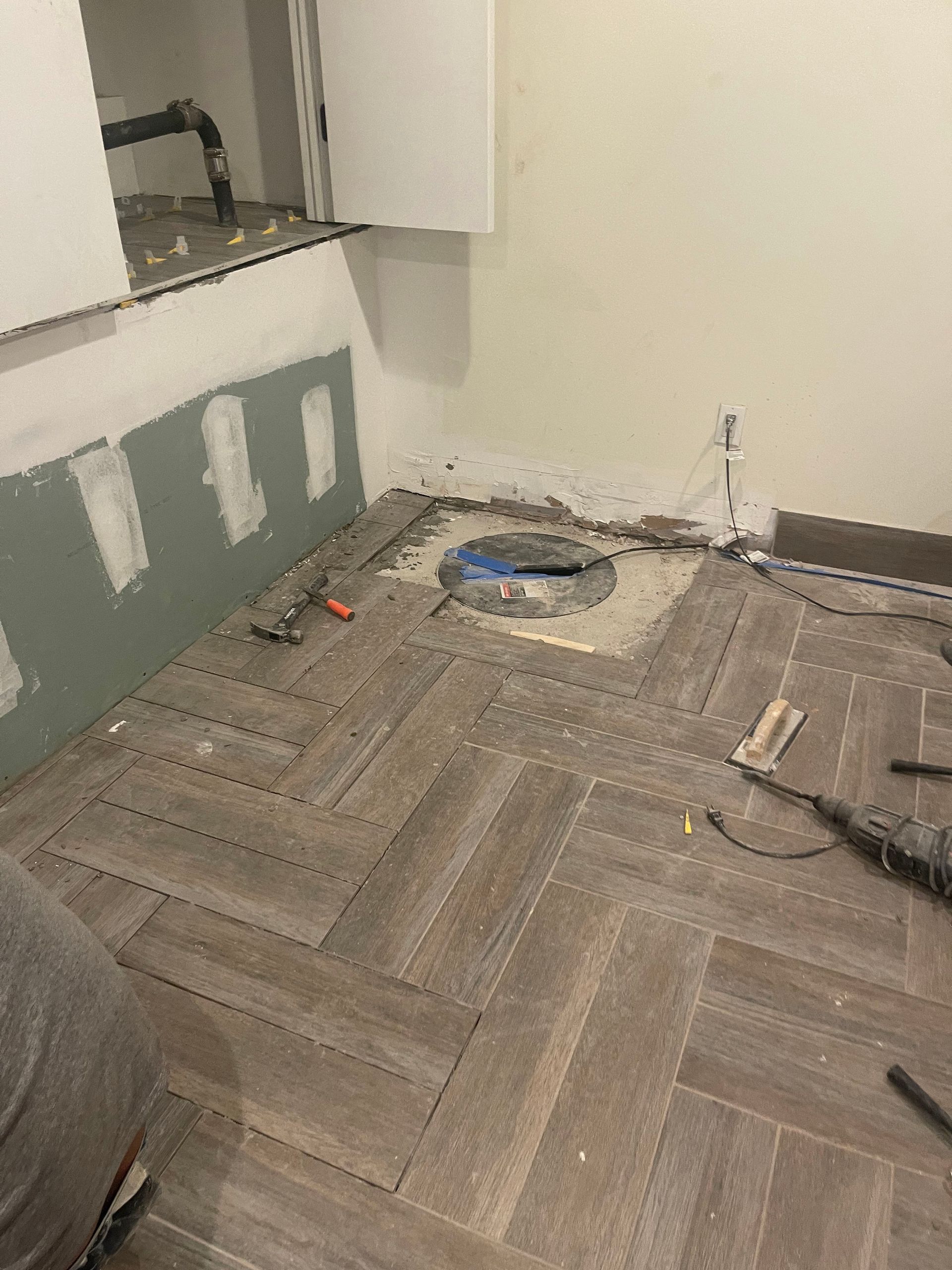 A bathroom under construction with a drill on the floor.