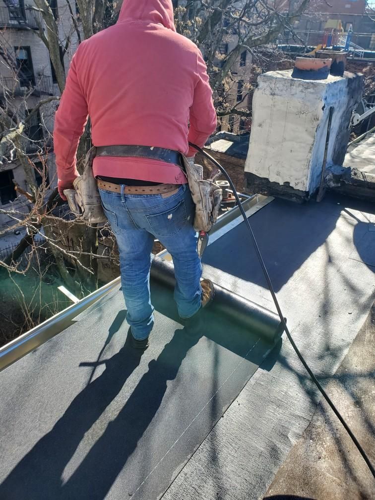 A man in a pink hoodie is standing on top of a roof.