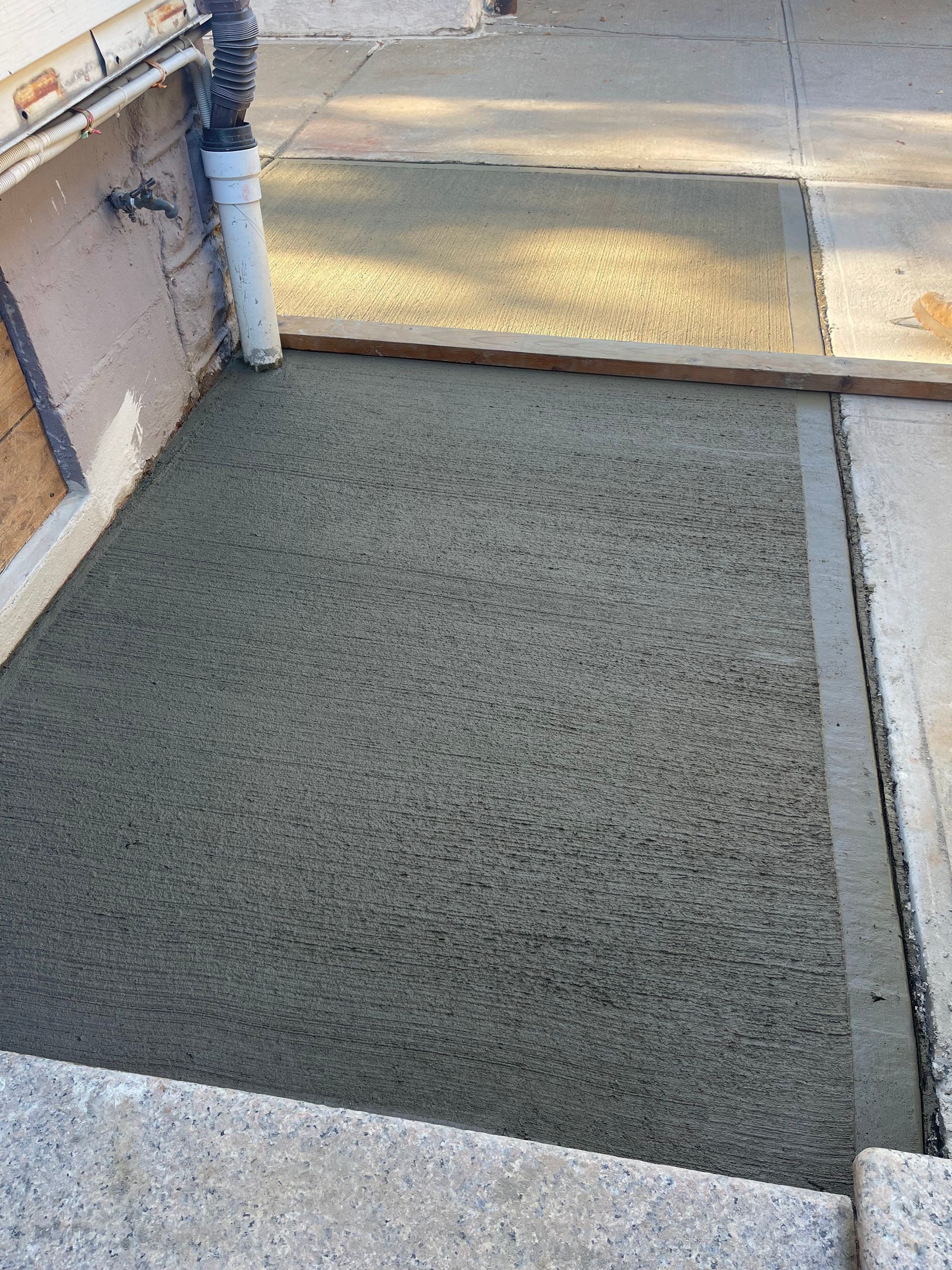 A concrete walkway is being built next to a house.