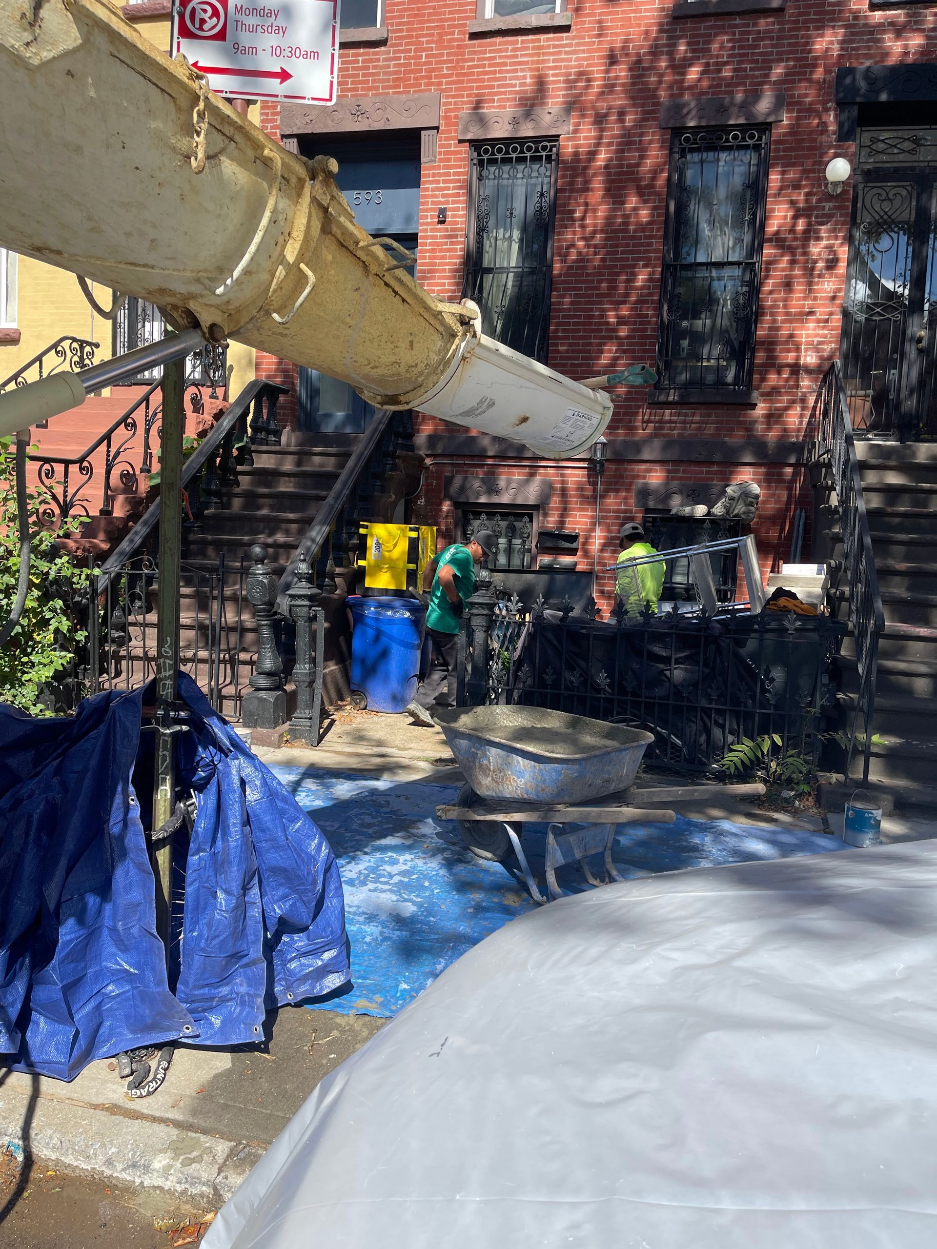 A group of people are working on a sidewalk in front of a brick building.