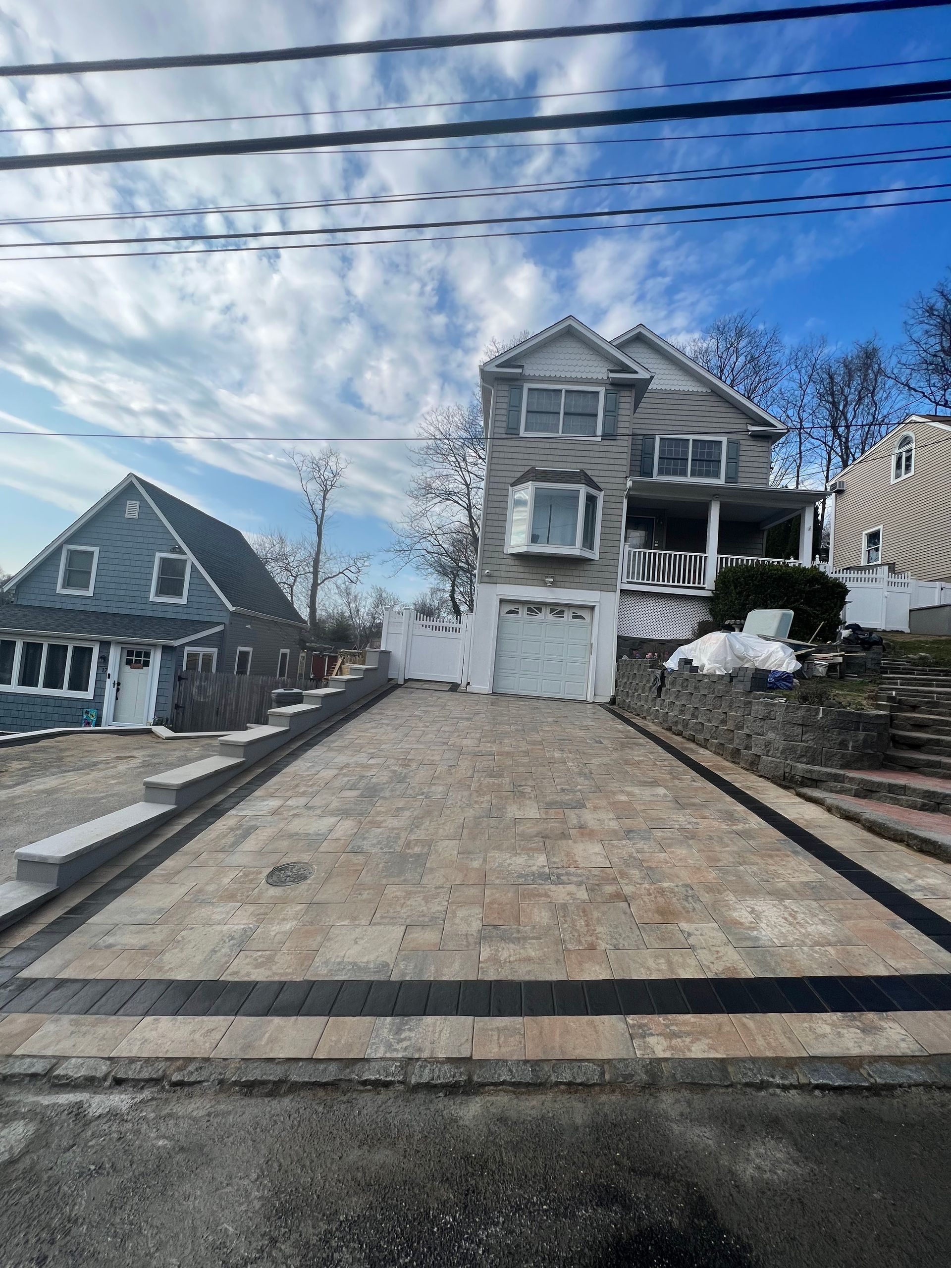 A brick driveway leading to a large house with a garage.