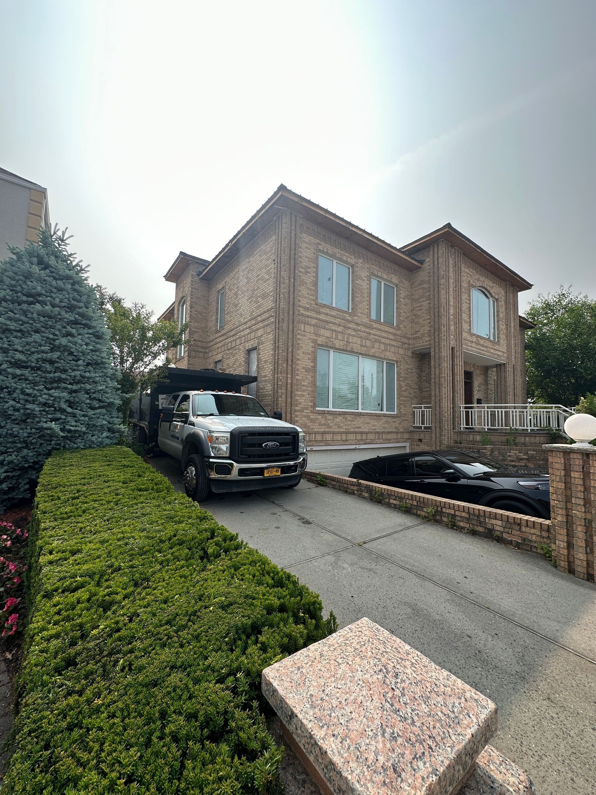 A white truck is parked in front of a large brick house.