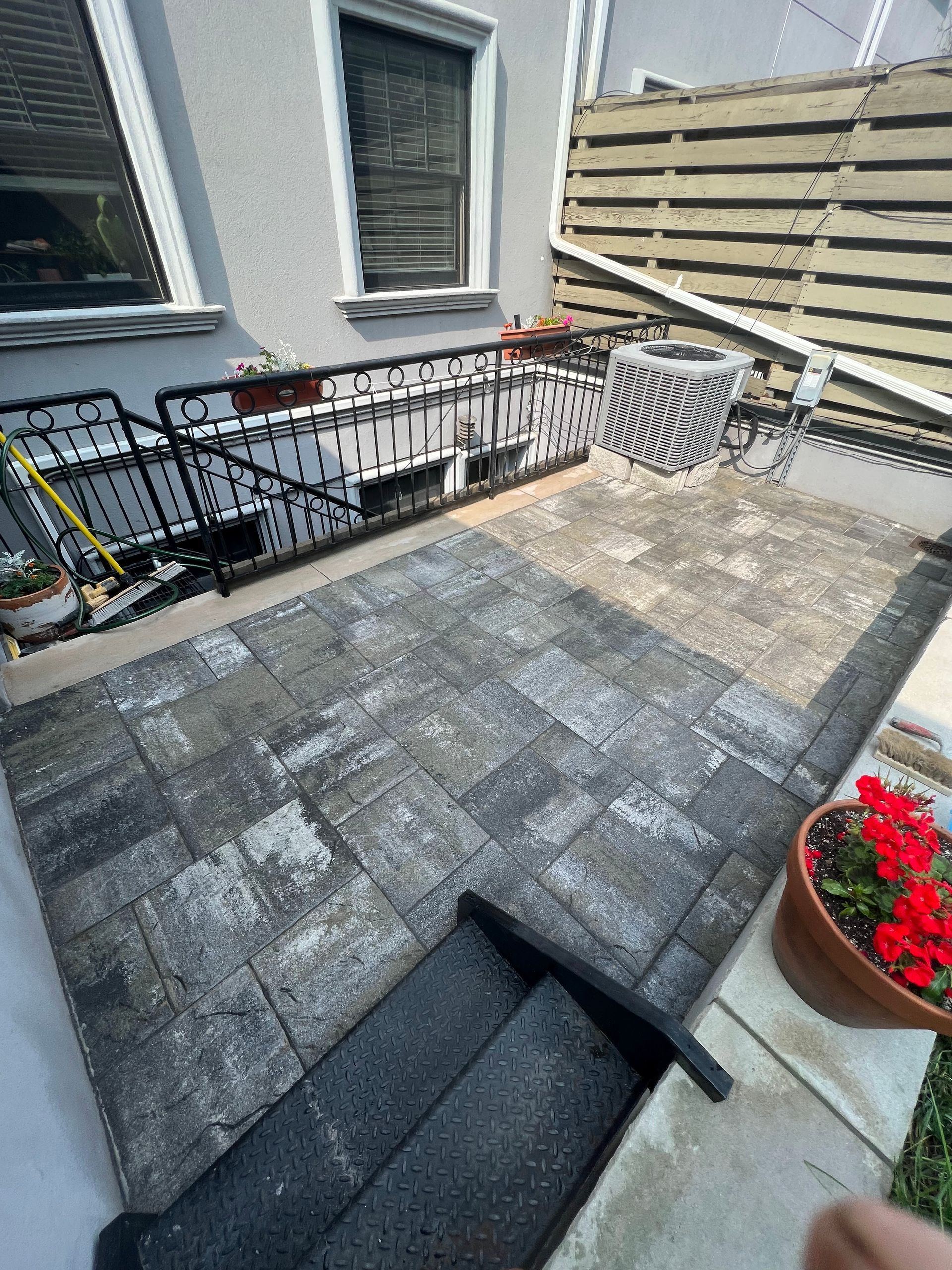 A person is standing on a patio with stairs and flowers.