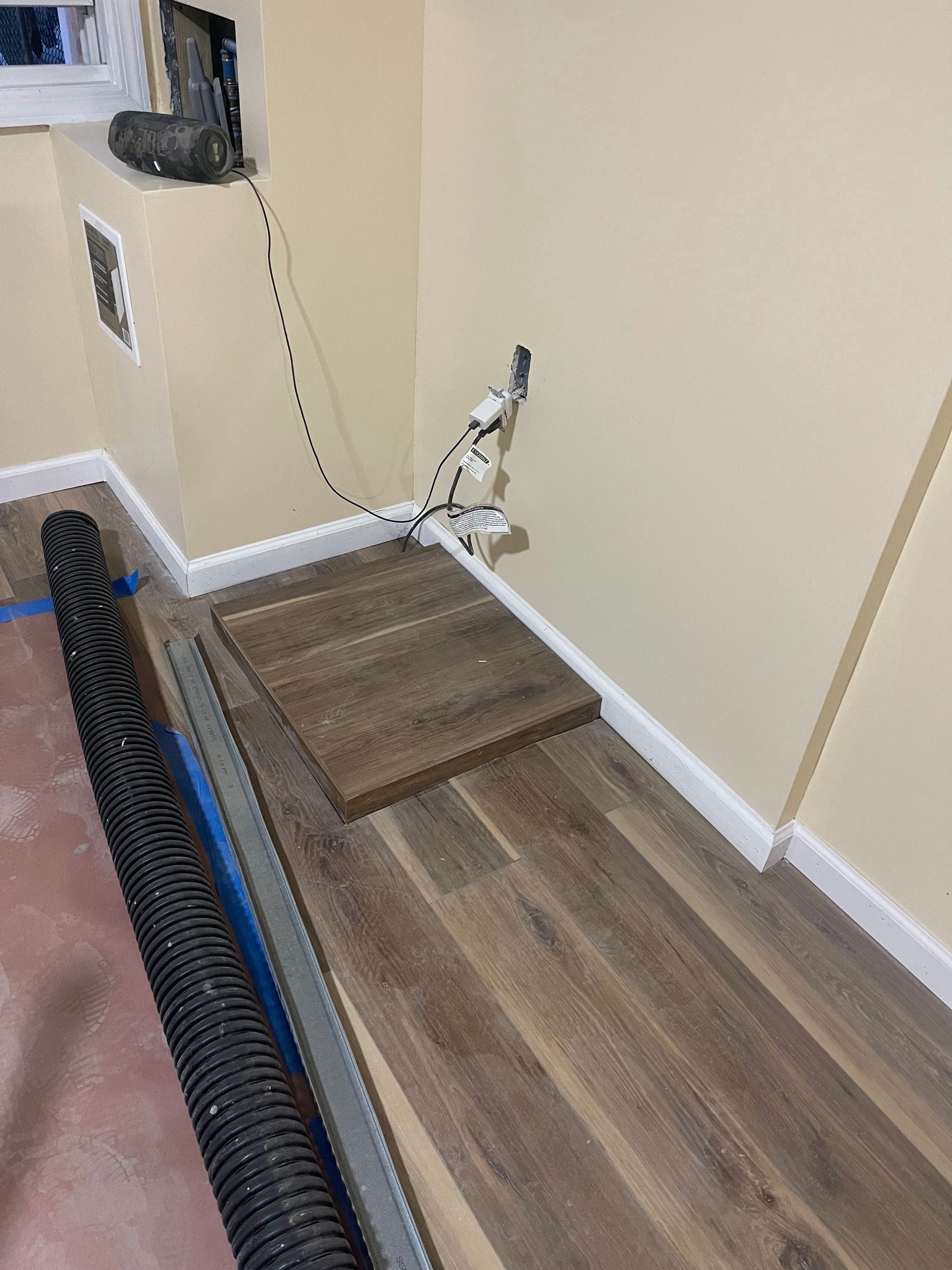 A room with a wooden floor and a vacuum hose.