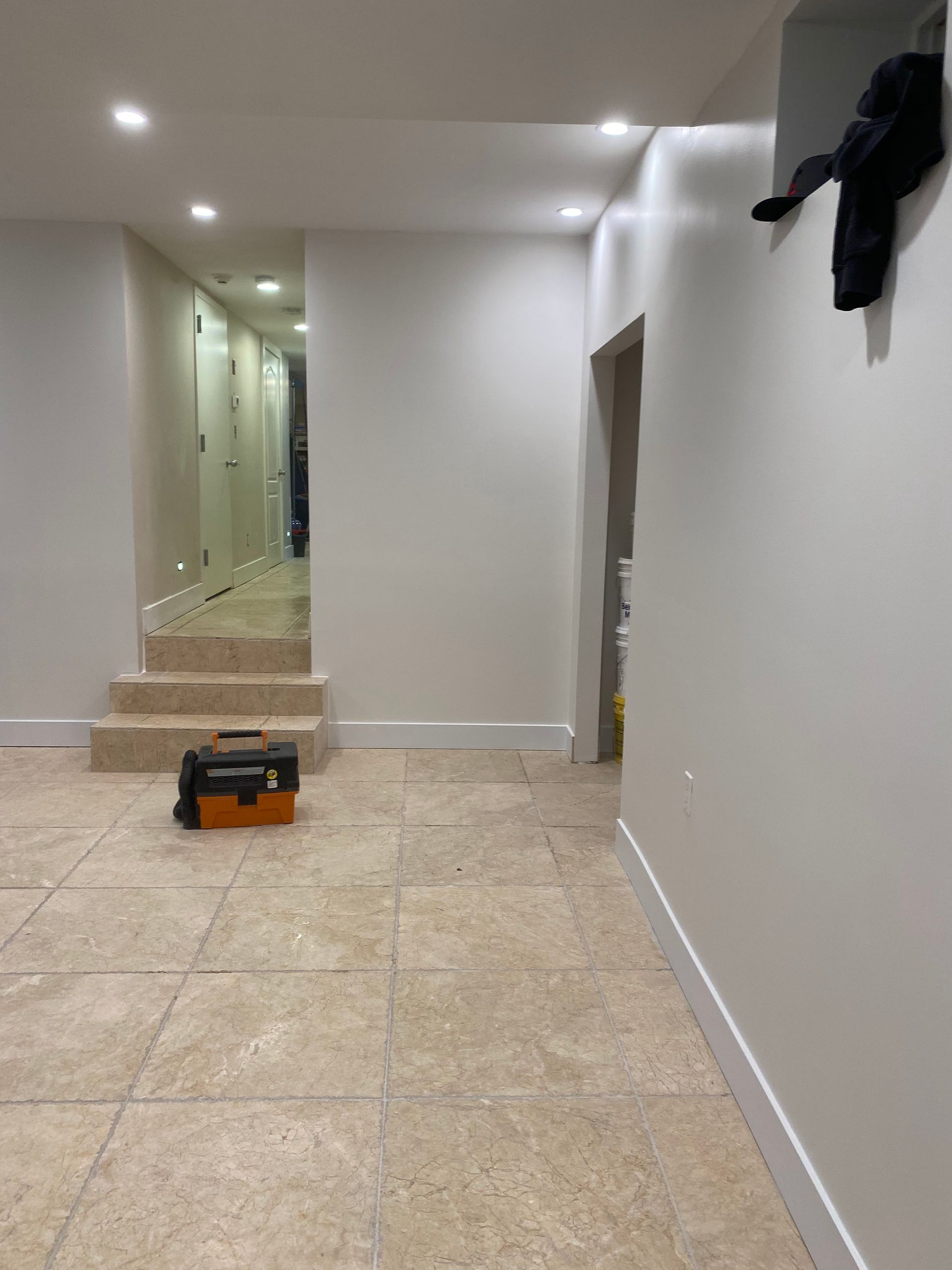 An empty hallway with stairs and a toolbox on the floor