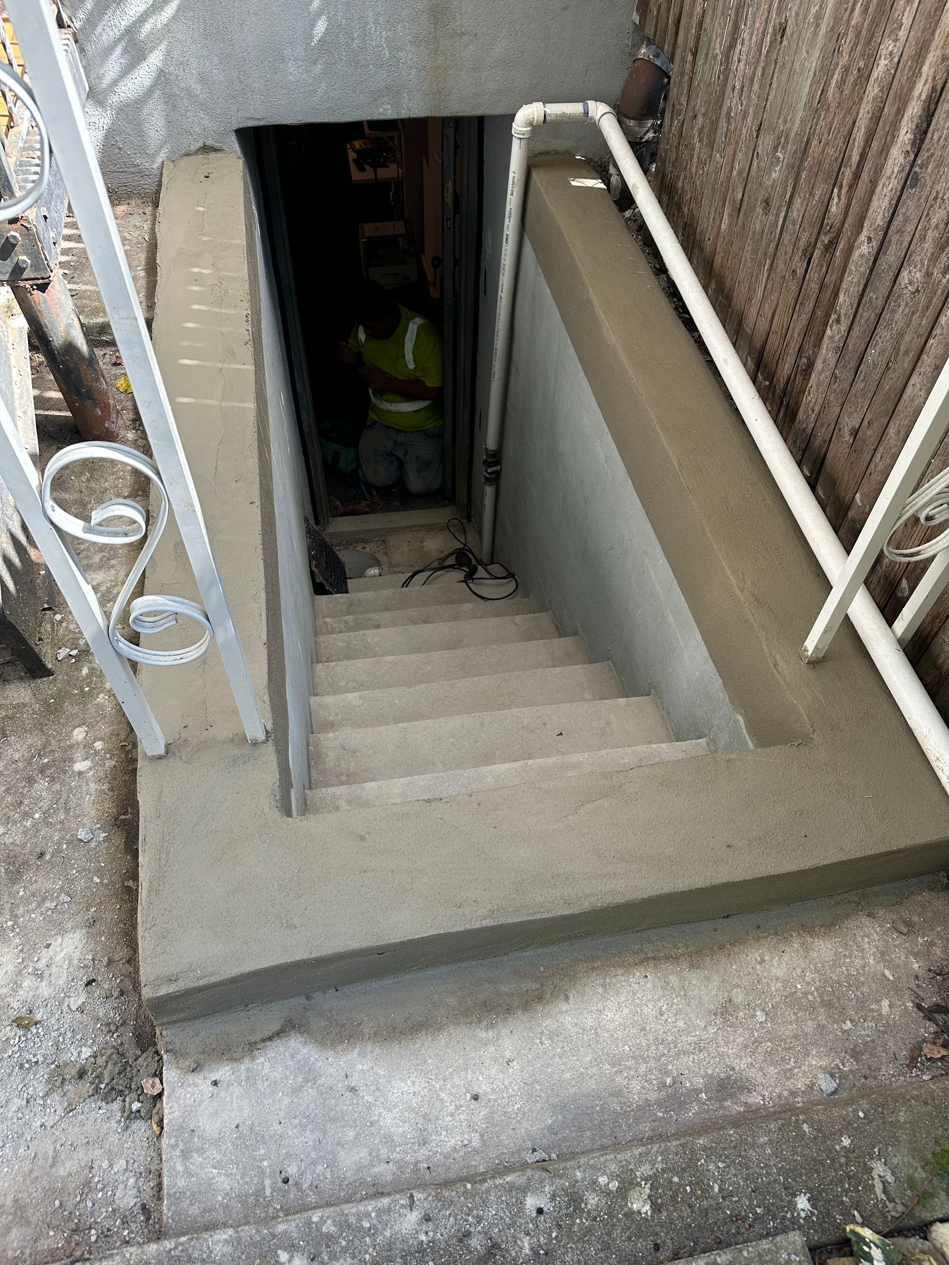 A man is walking down a set of stairs in a basement.