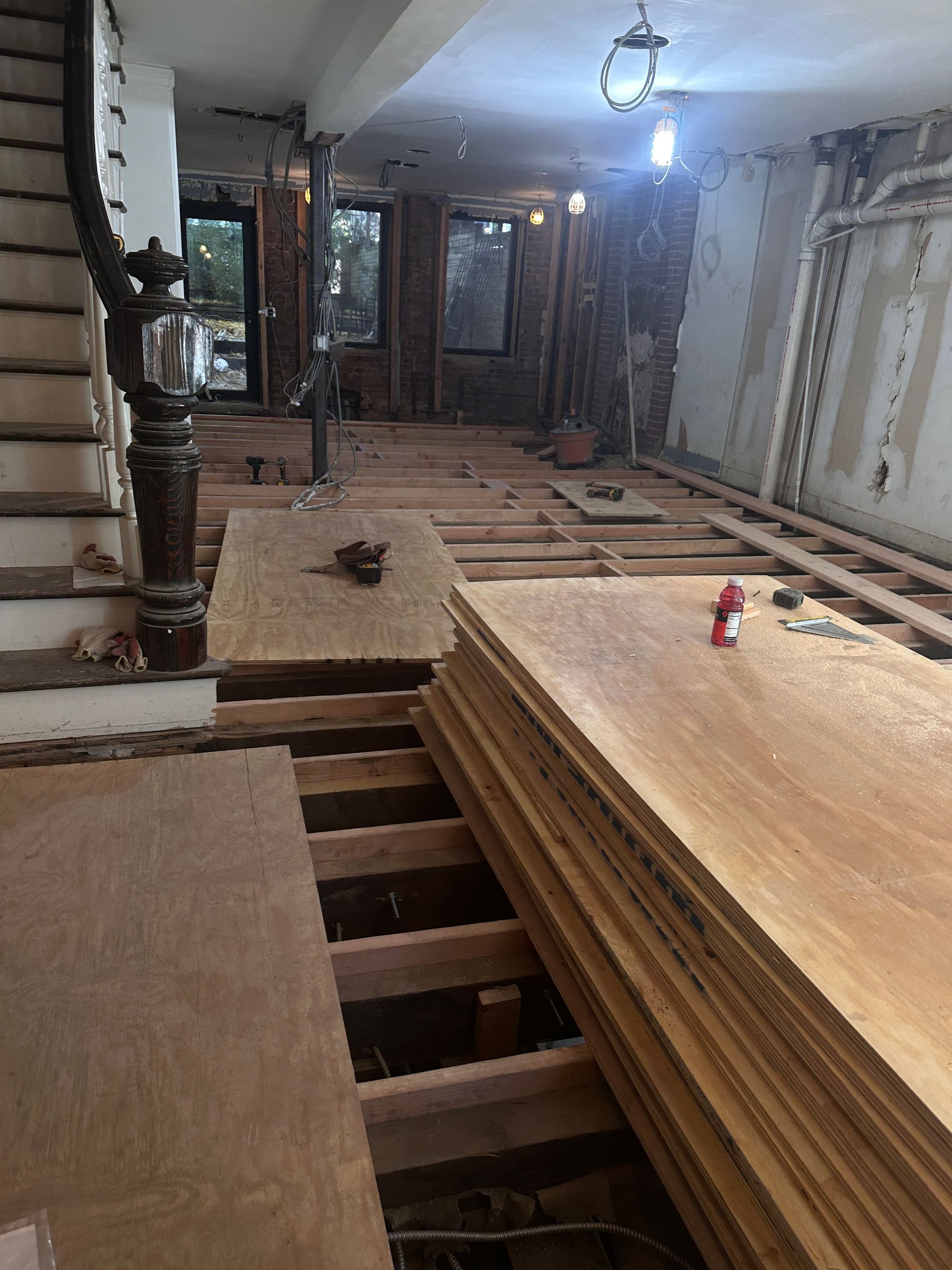 A room with a staircase and a stack of plywood on the floor.