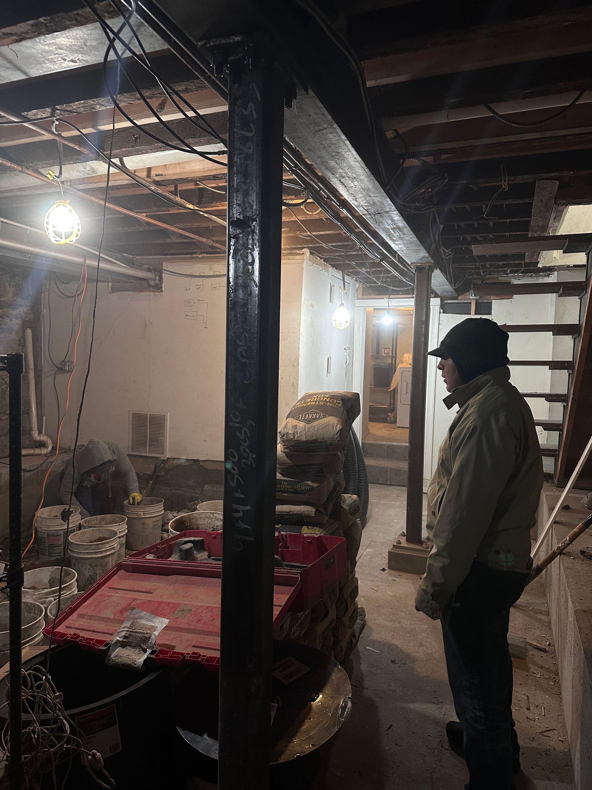 A man is standing in a basement next to a table and stairs.