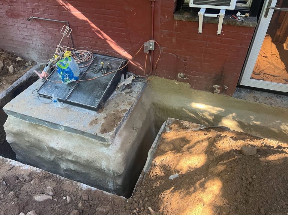 A concrete block is sitting in the dirt in front of a brick building.