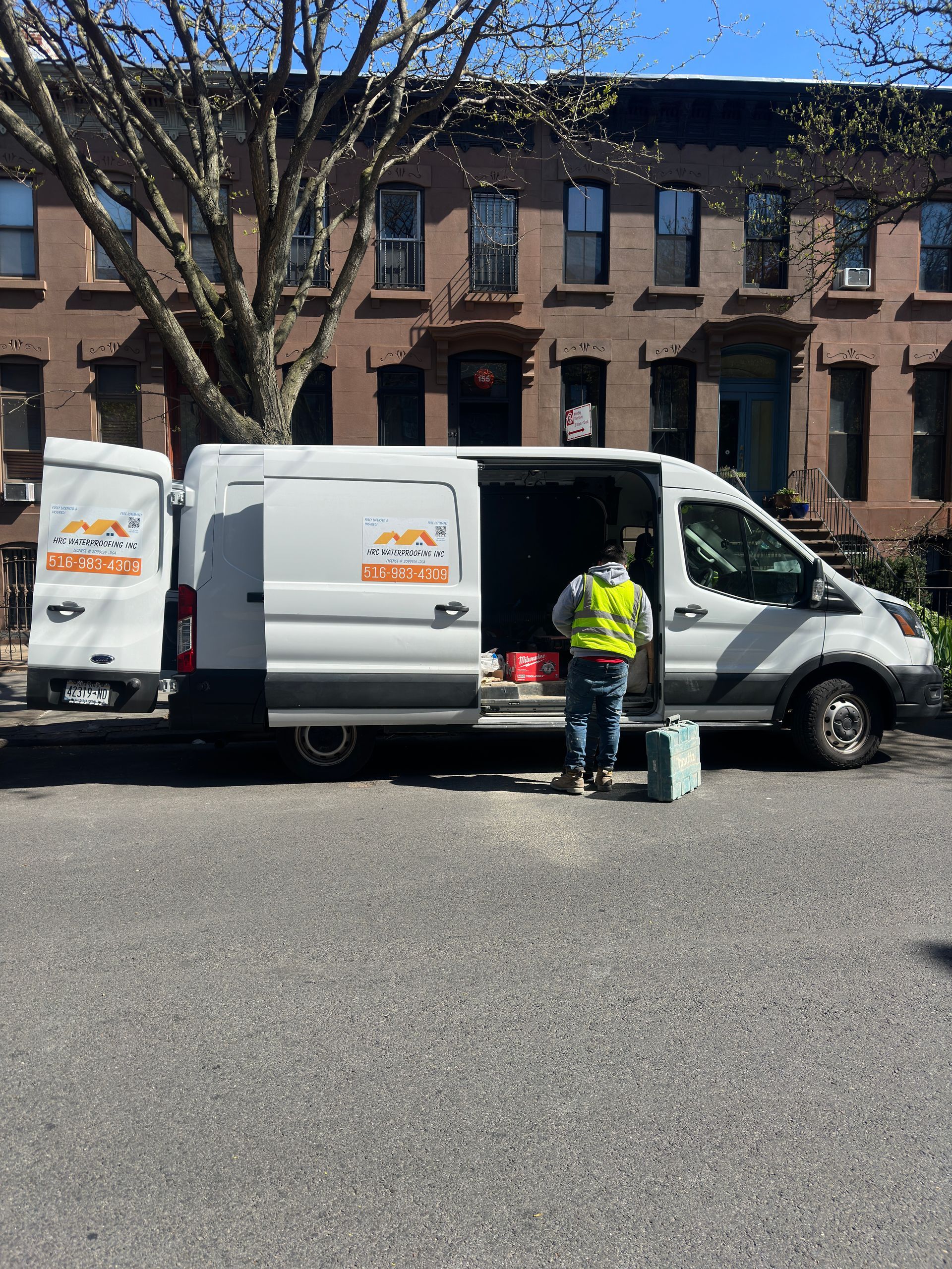 Two white vans are parked in front of a brick building