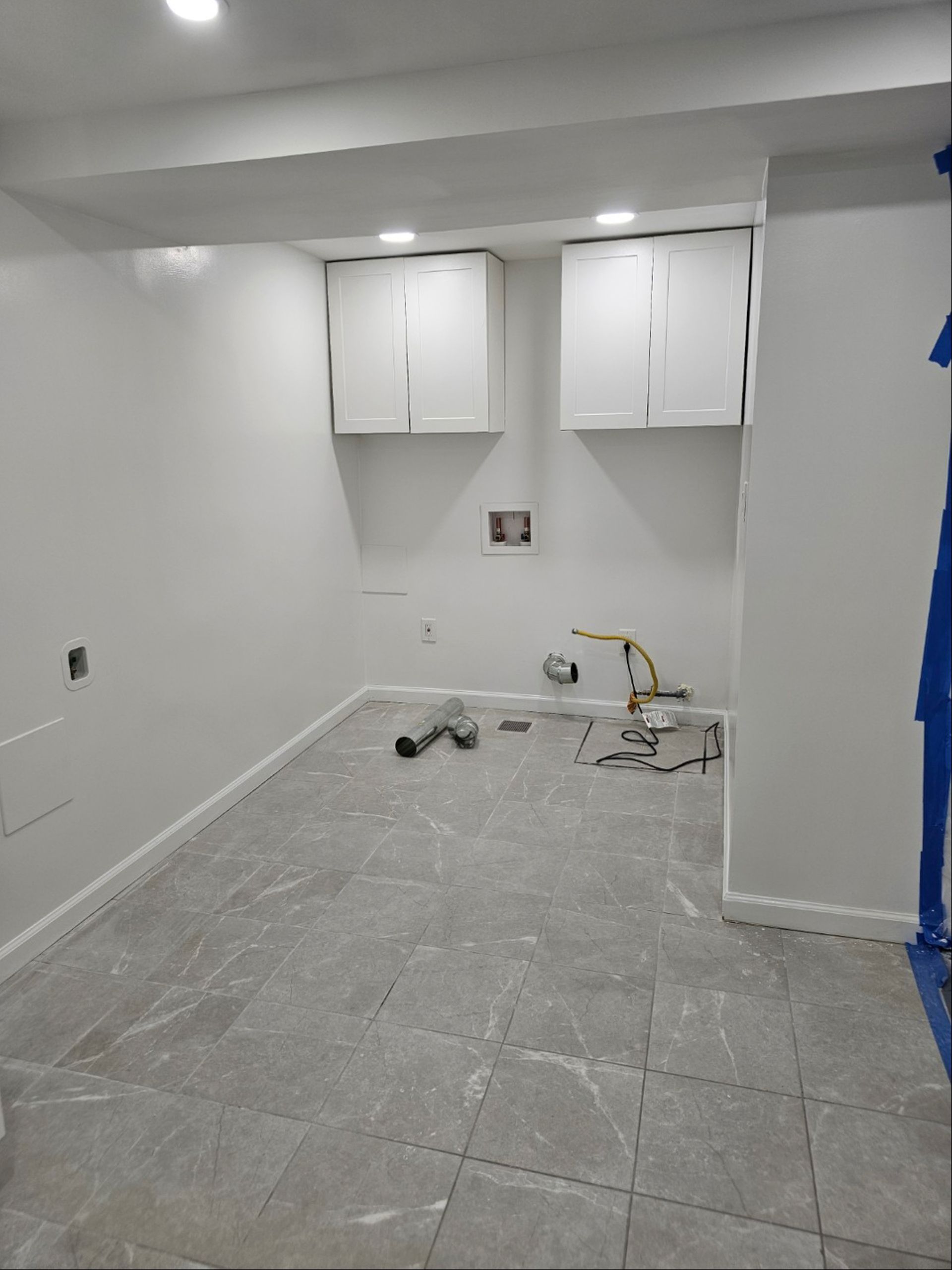 A room with white walls and tile floors is being remodeled.