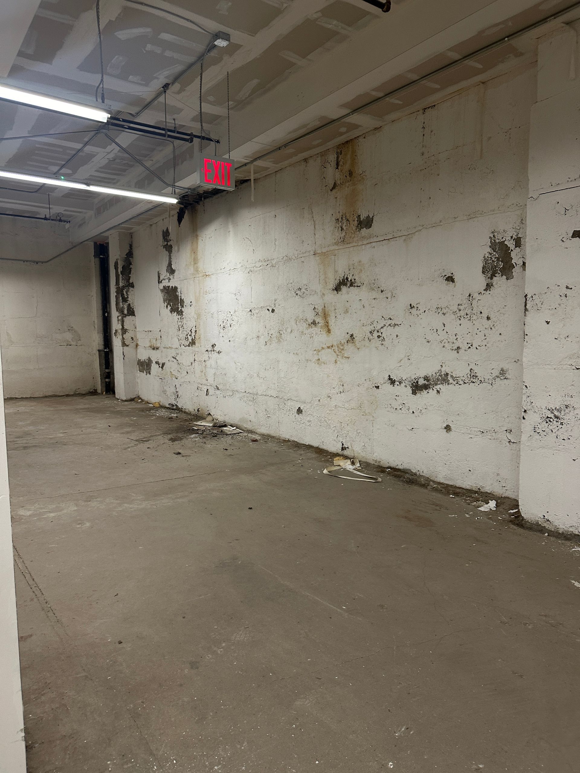 An empty room with a red exit sign hanging from the ceiling.