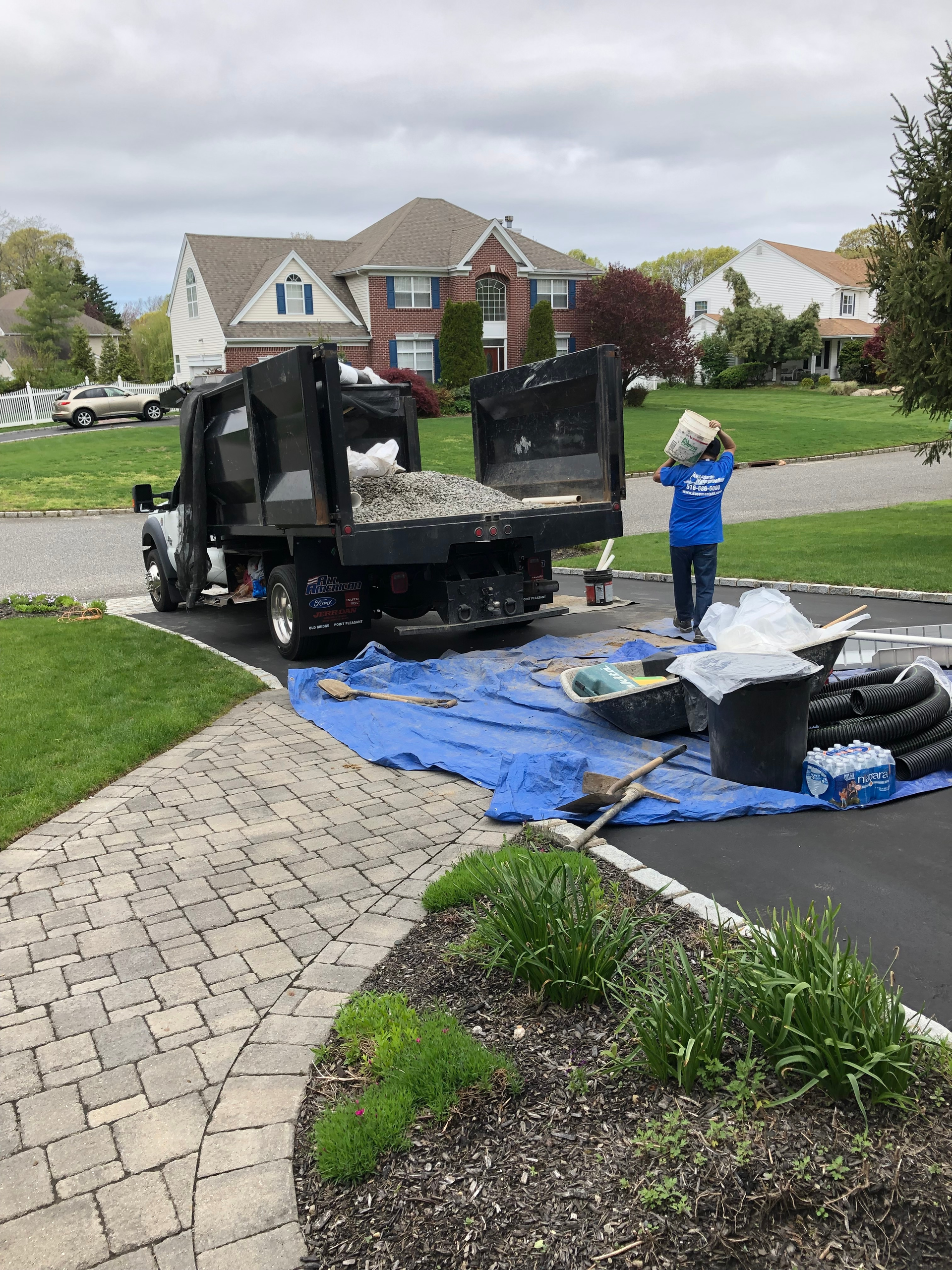 A dump truck is sitting on top of a blue tarp in front of a house.
