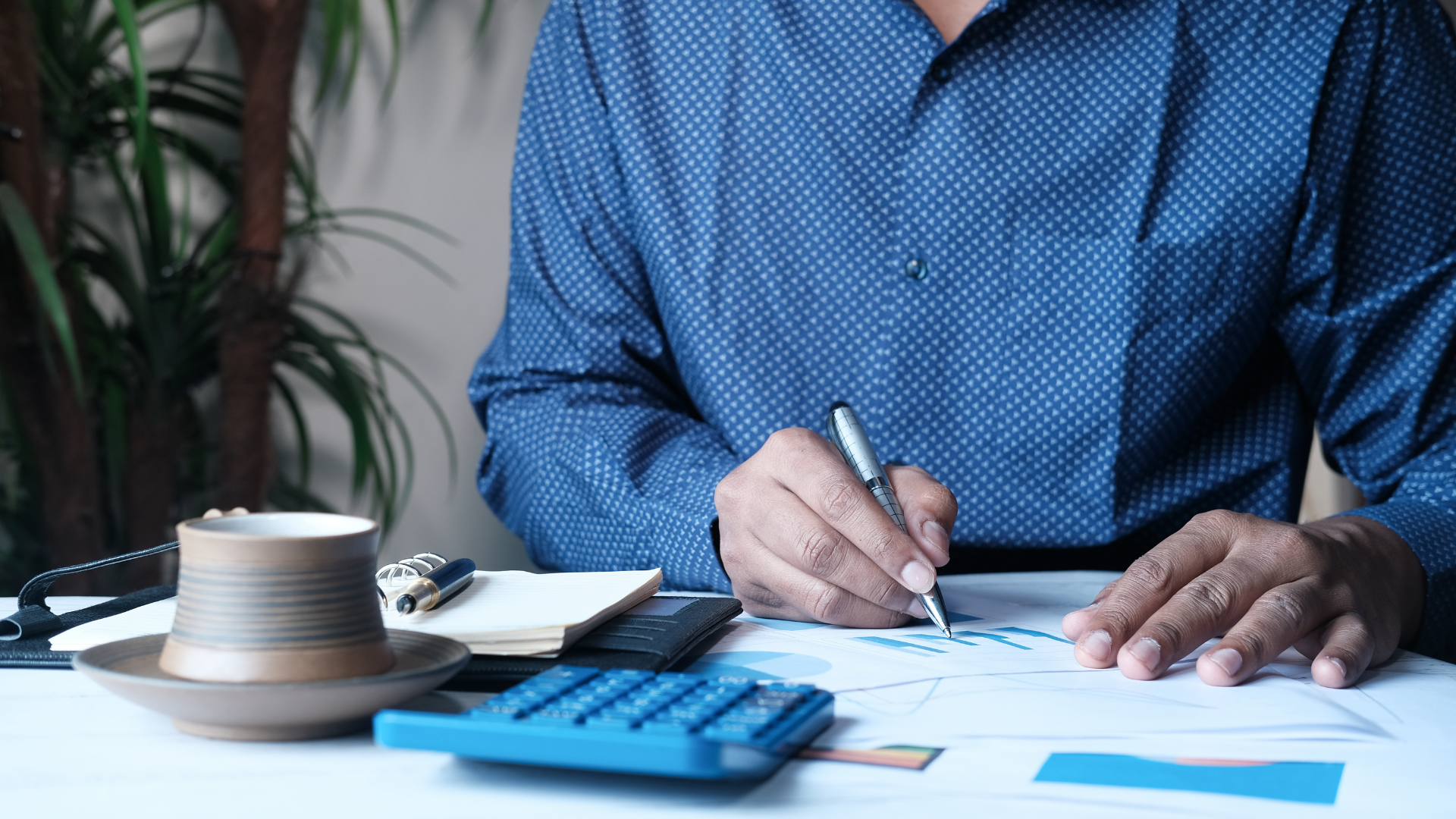 A man is sitting at a desk writing on a piece of paper.