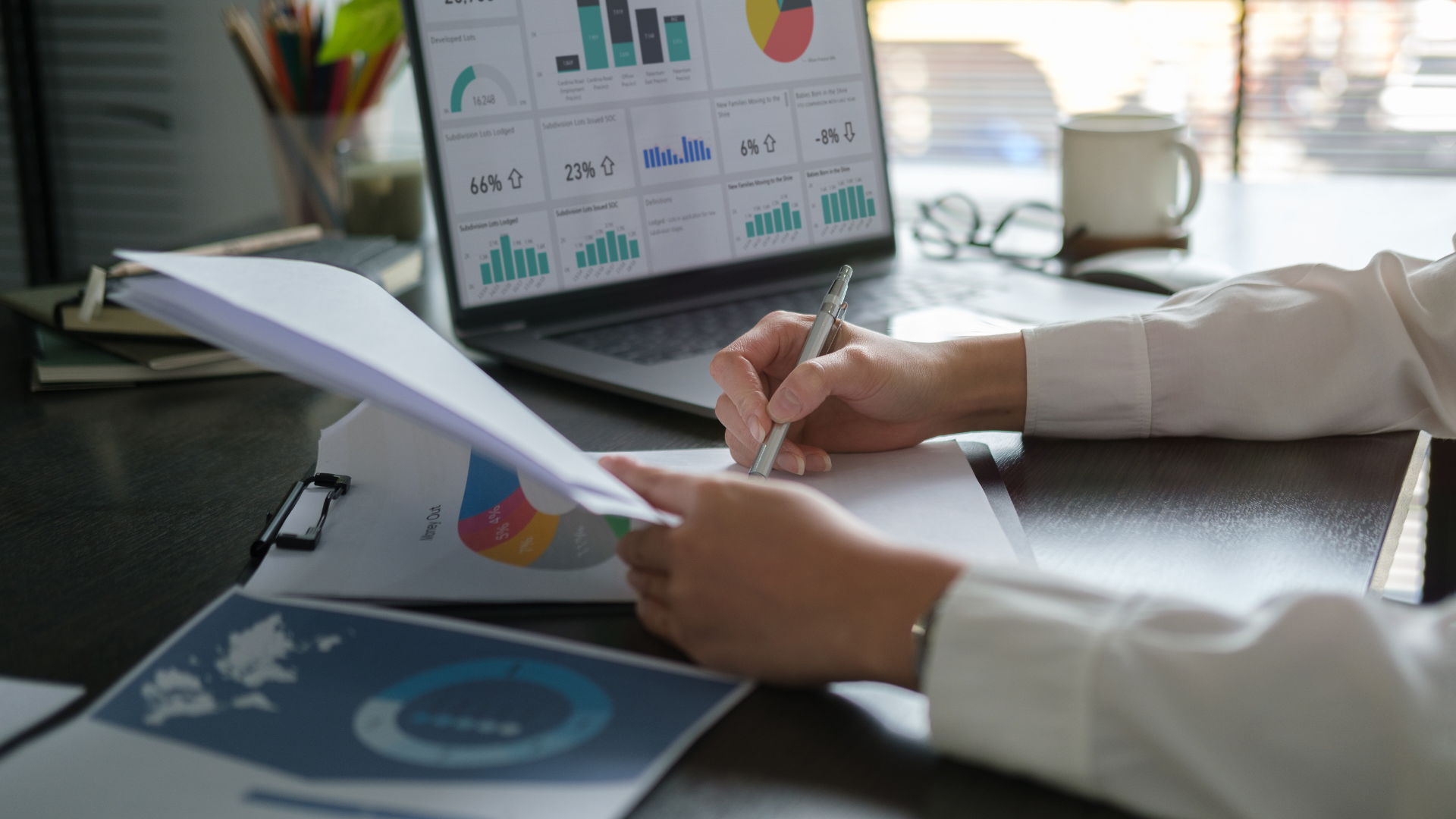 A person is sitting at a desk with a laptop and papers.