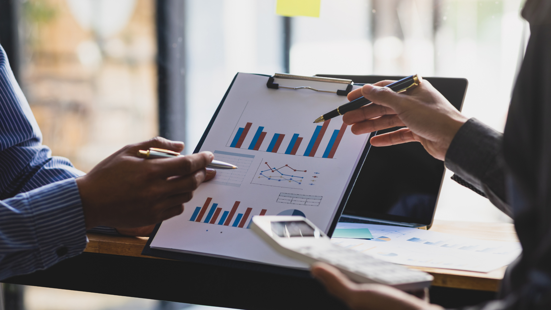 A man and a woman are looking at a clipboard with a graph on it.