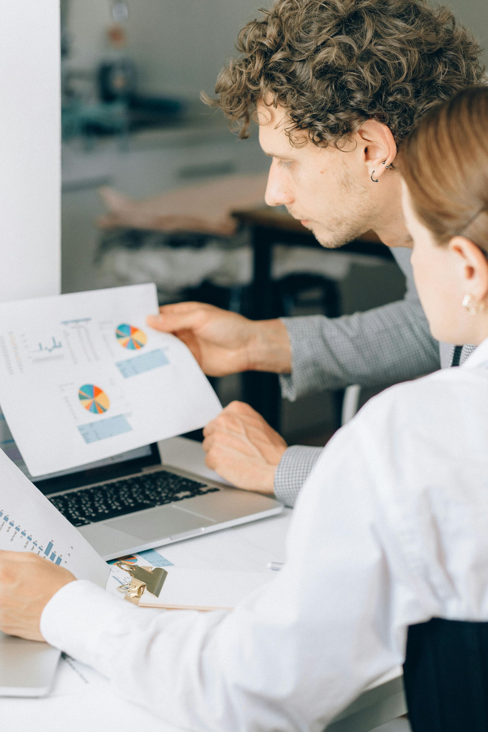 Two people reviewing financial documents together at a desk with a laptop.