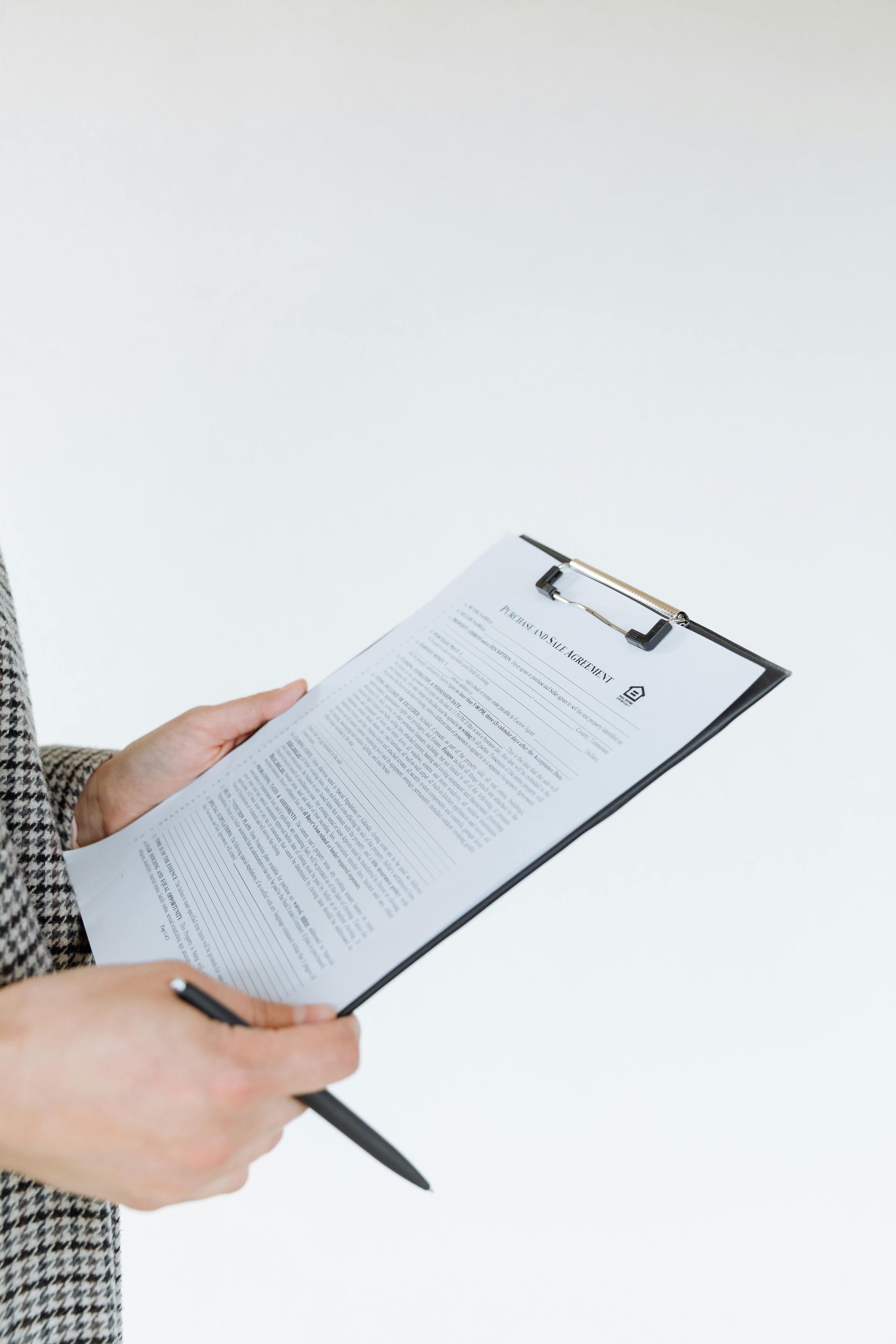 Person holding a clipboard with document and a pen against a white background.