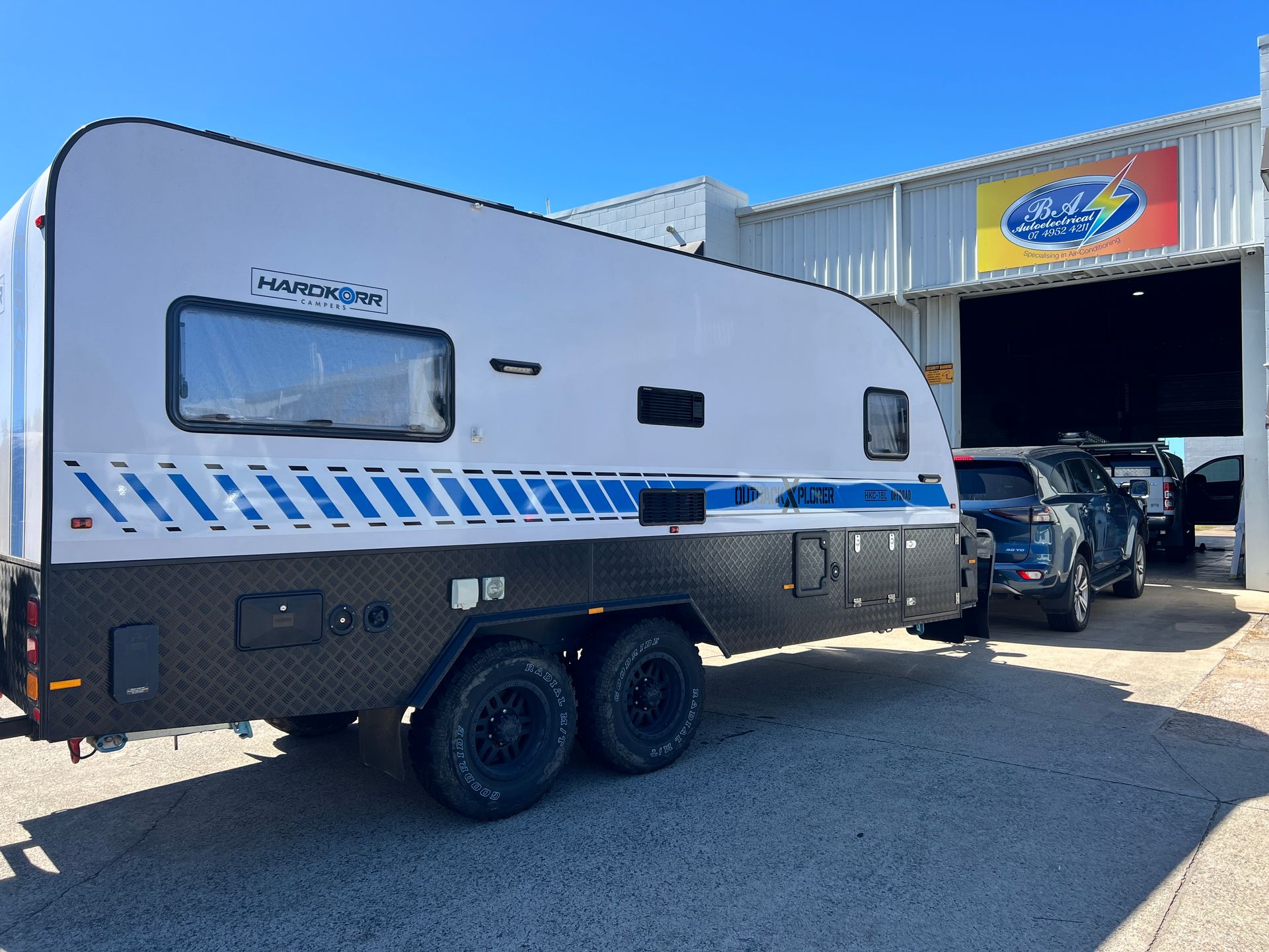White and black caravan with blue accents parked in front of a garage.— BA Auto Electrical In West Mackay, QLD