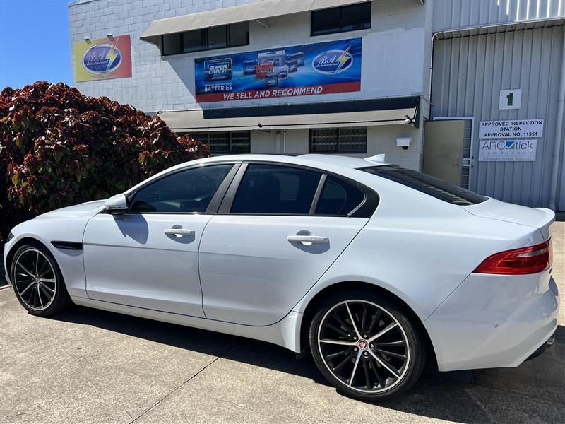 White Jaguar sedan parked outside a building with signage; sunny day.— BA Auto Electrical In West Mackay, QLD