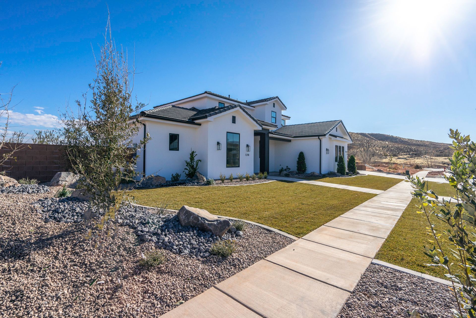 A large white house with a concrete walkway leading to it.