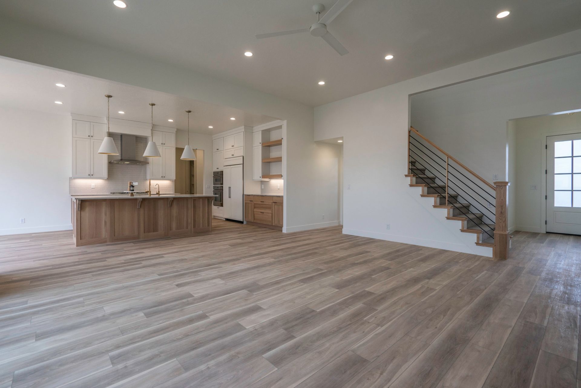 A large empty room with hardwood floors and stairs in a house.