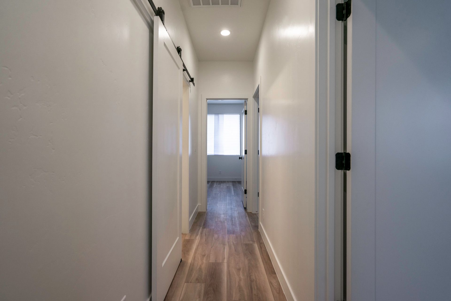 A long hallway with sliding barn doors leading to a bedroom.