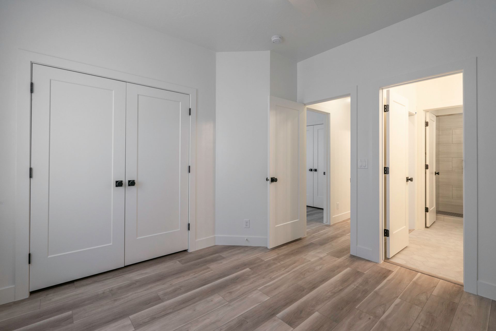An empty bedroom with hardwood floors and white walls.