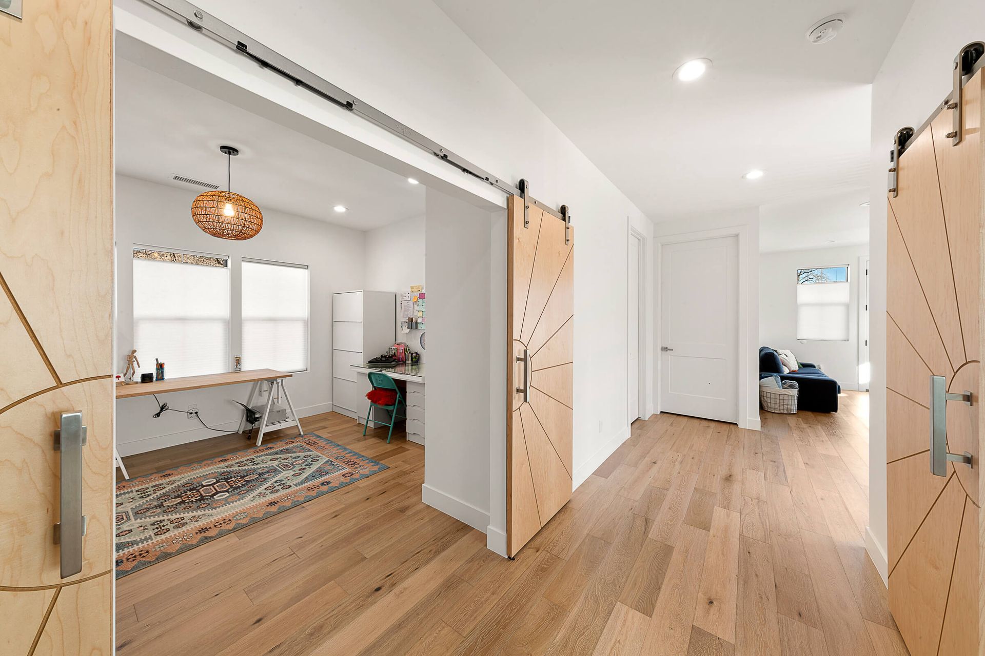 A hallway in a house with wooden floors and sliding barn doors.