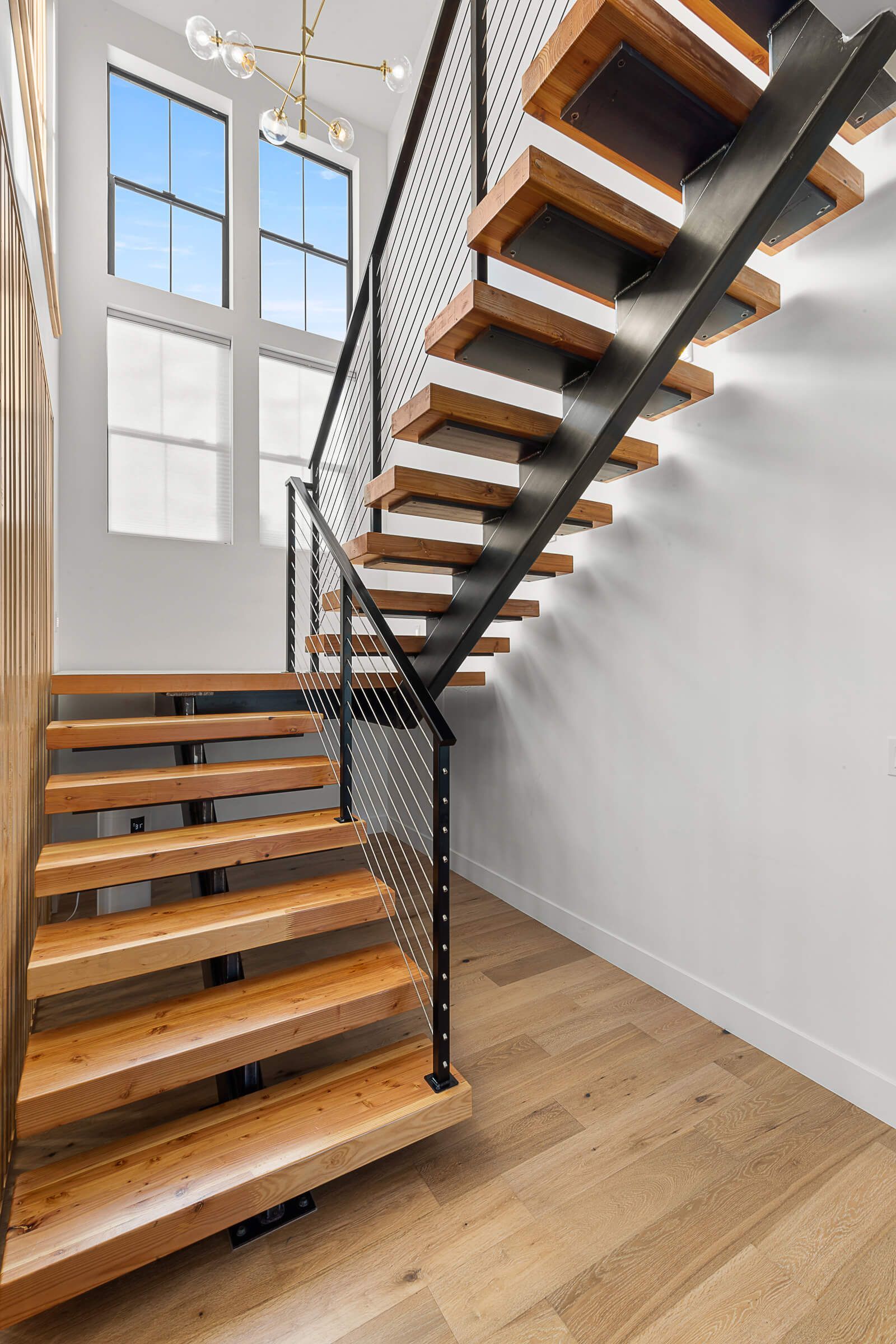 A modern staircase with wooden steps and a metal railing in a house.