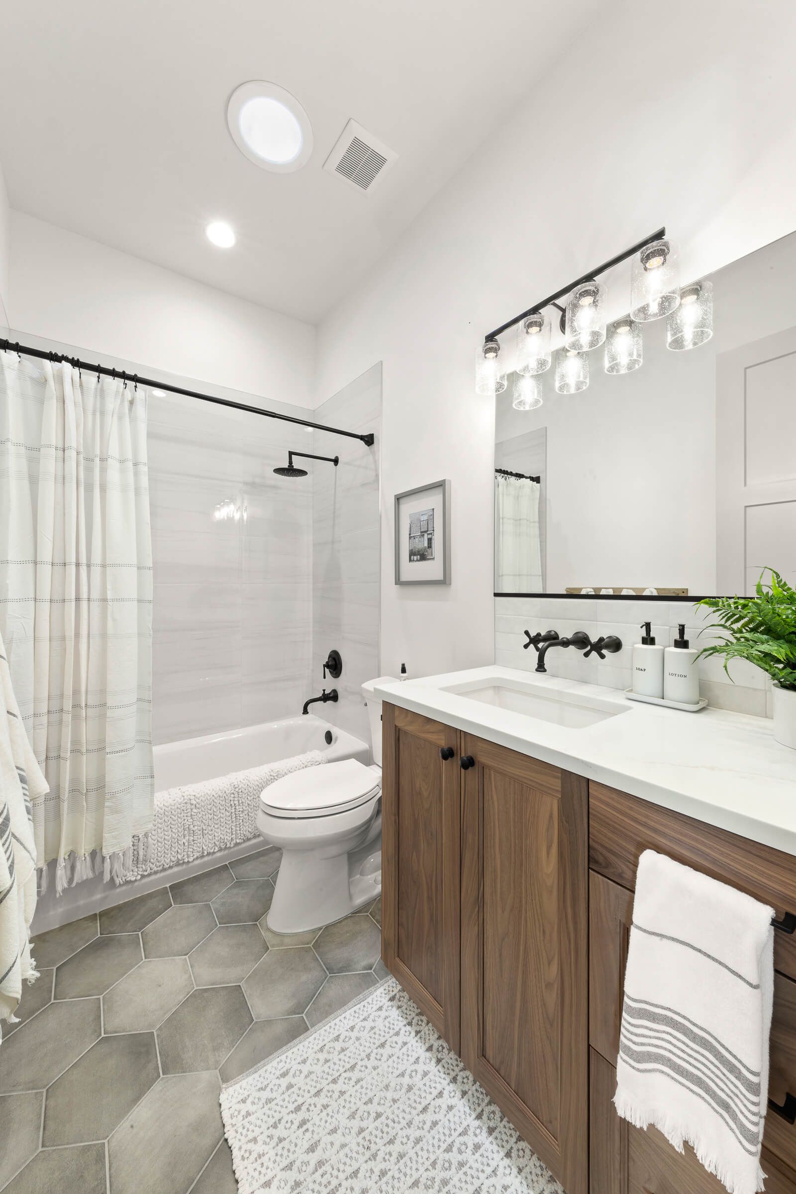 A bathroom with a sink , toilet , bathtub and mirror.