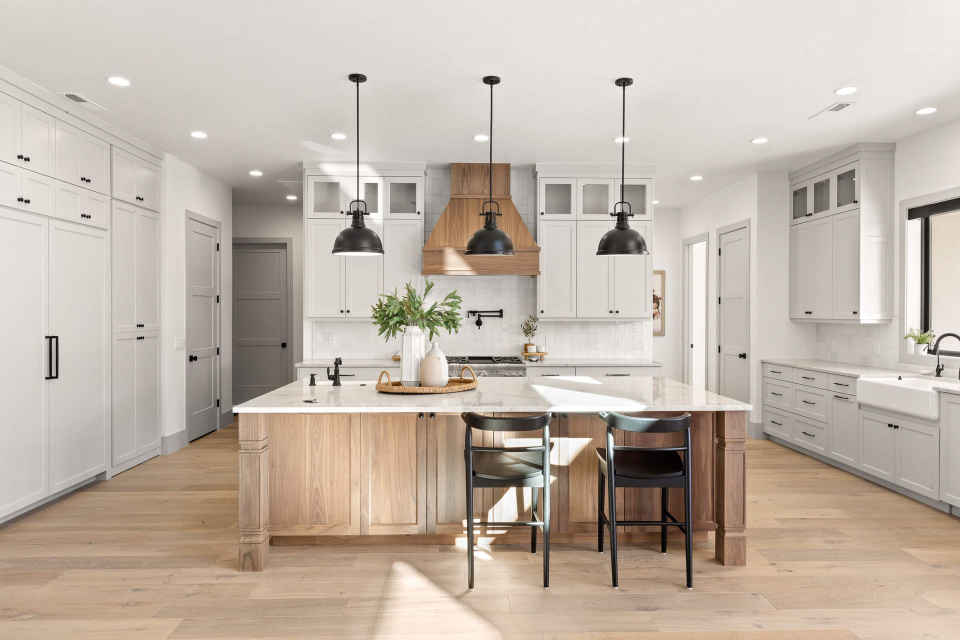 A kitchen with white cabinets , wooden floors , and a large island.