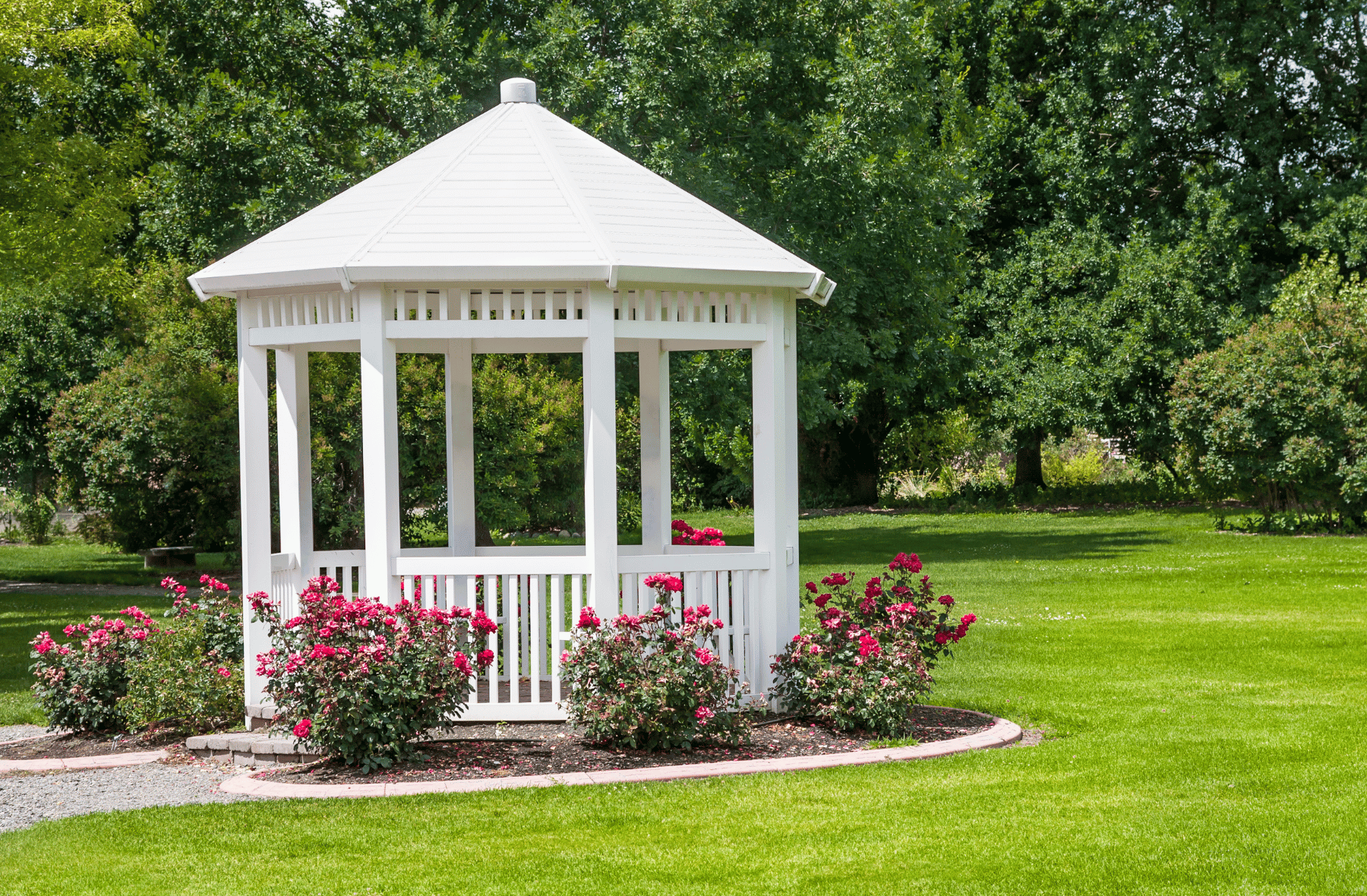 A white gazebo is sitting in the middle of a lush green field.