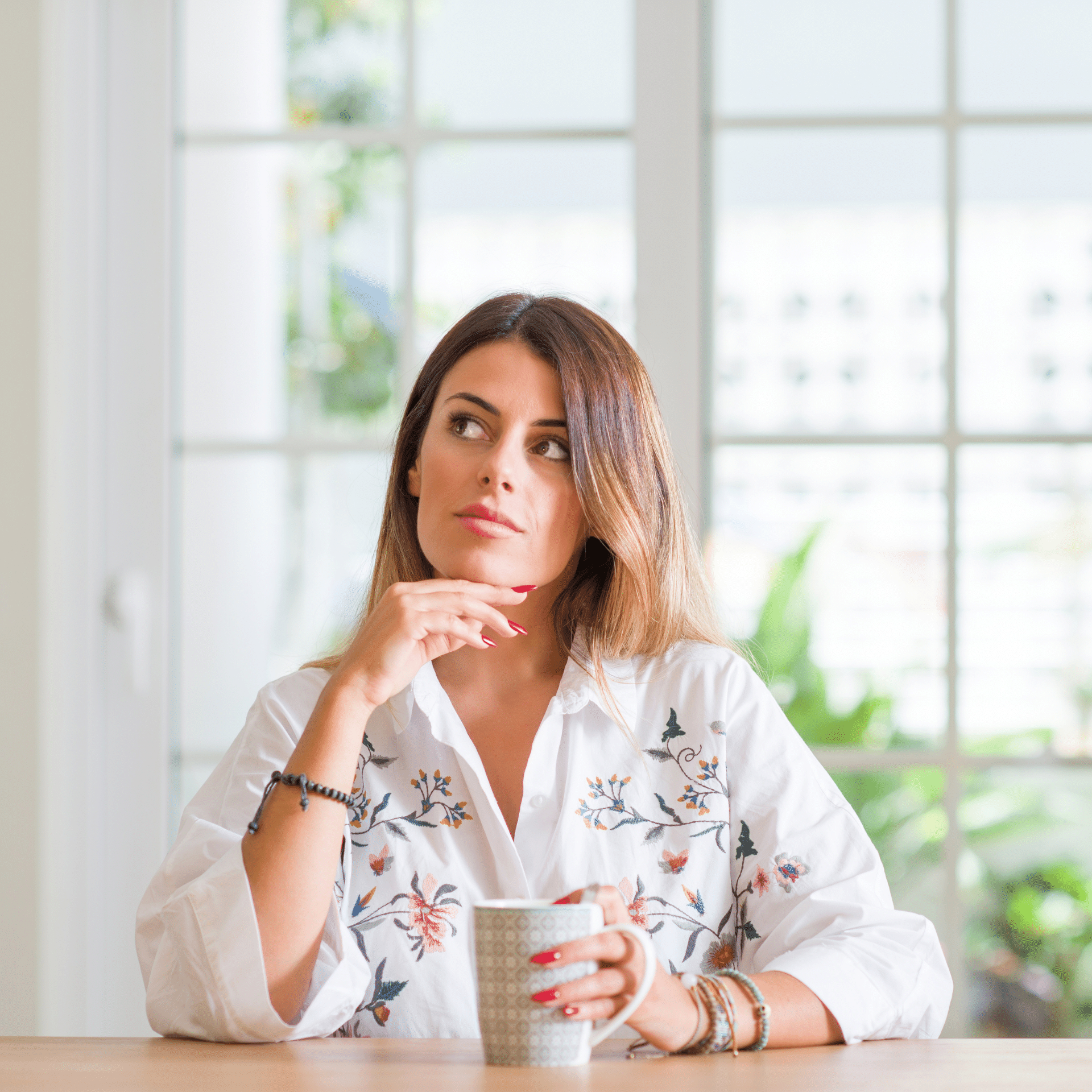 A woman is sitting at a table holding a cup of coffee.