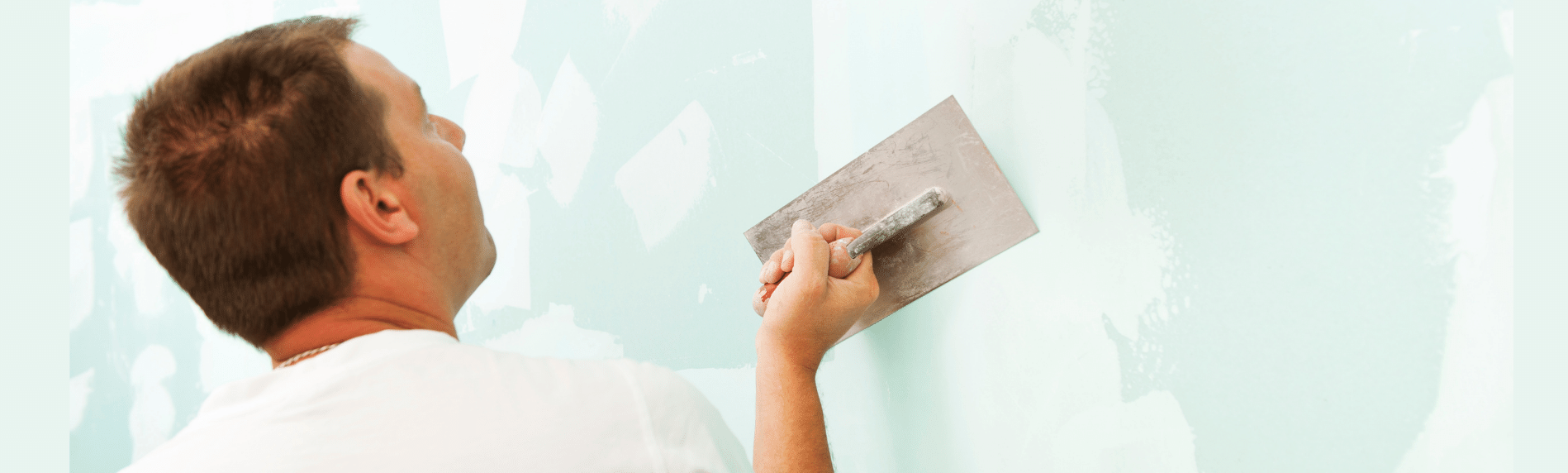 A man is plastering a wall with a trowel.