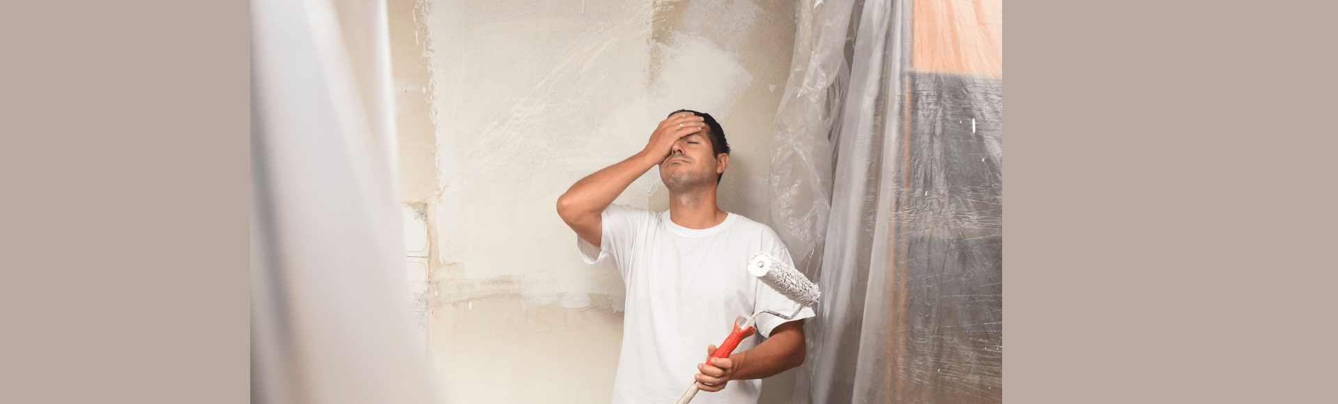 A man is standing in a room holding a paint roller.