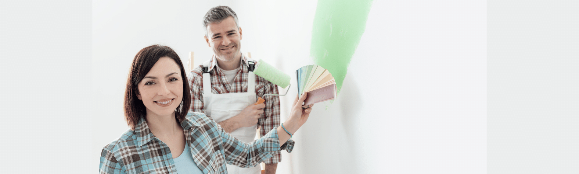 A man and a woman are painting a wall together.