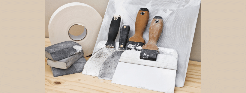 A wooden table topped with a spatula , sandpaper , and tape.