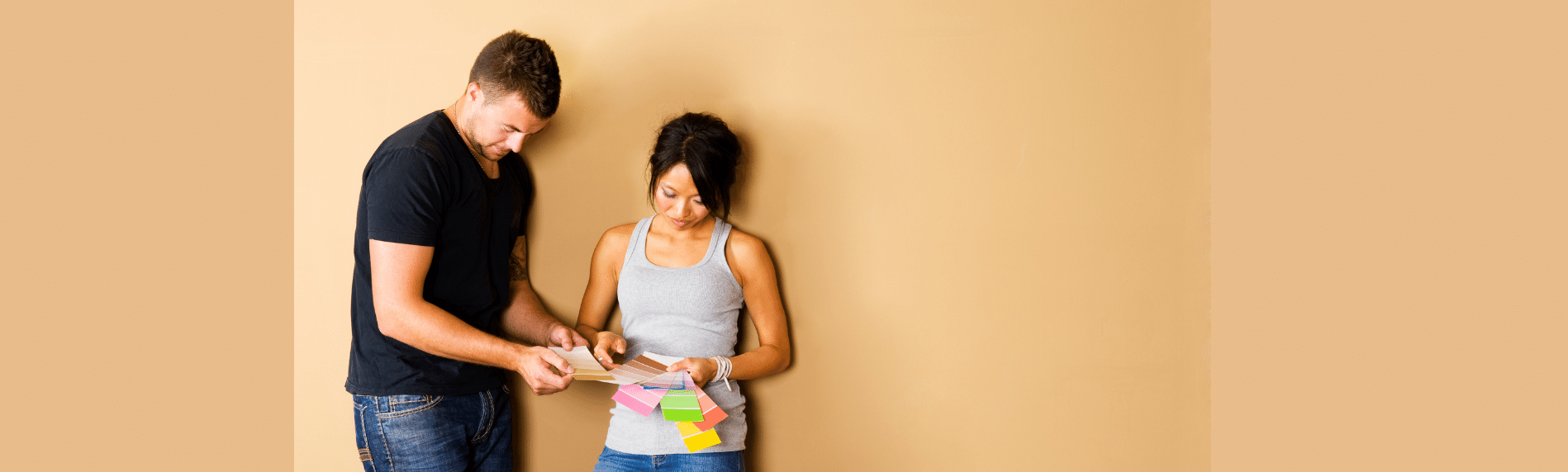 A man and a woman are standing next to each other in front of a wall.