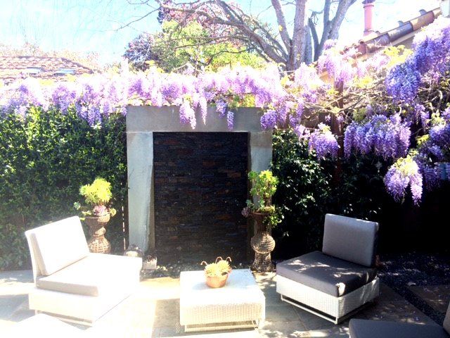 patio with wisteria framed stone waterfall