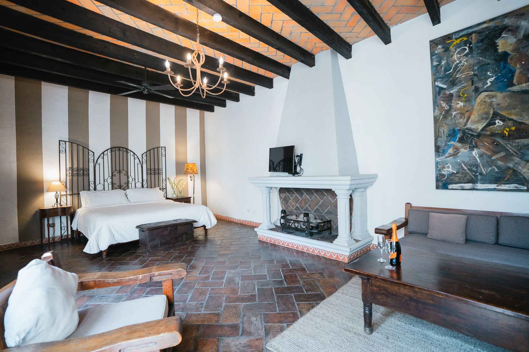 Dormitorio con cama, chimenea, sofá y un gran cuadro abstracto.